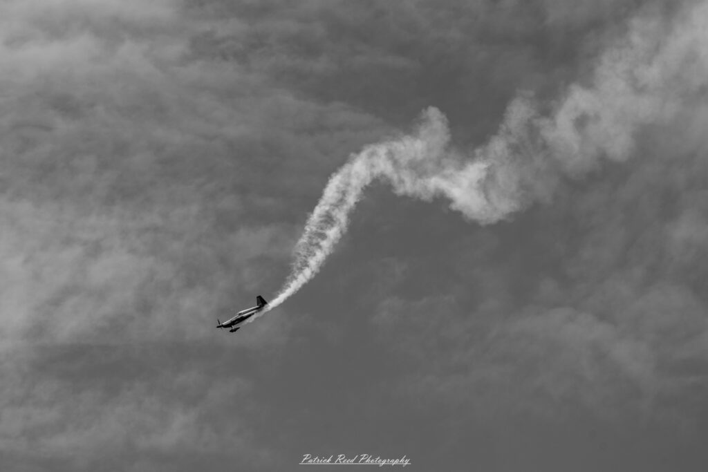 "An aerobatic performance plane, designed for precision flying and stunning aerial maneuvers, showcased in mid-flight. The aircraft features a sleek, lightweight design with bright, eye-catching colors and distinctive markings that highlight its agility. With its short wingspan and powerful engine, the plane performs impressive tricks such as loops, rolls, and spins against a clear blue sky. Smoke trails may be visible behind it, enhancing the dynamic nature of the performance as the pilot demonstrates exceptional skill and control during the thrilling aerial display."