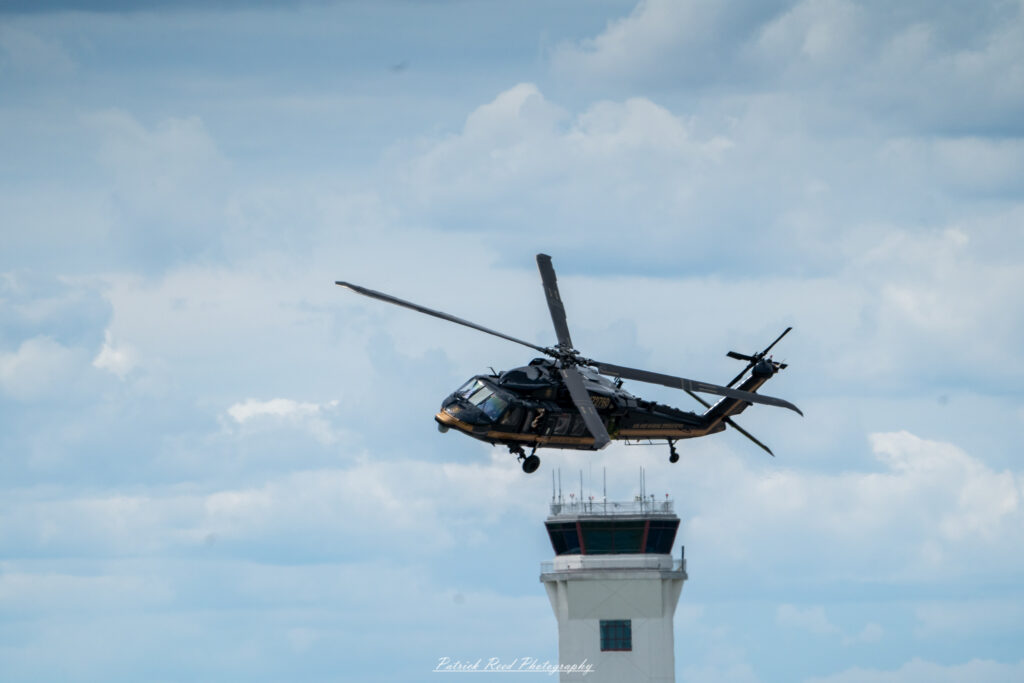 "The Black Hawk helicopter, a versatile and iconic military aircraft, is depicted in a dynamic flying pose against a clear sky. Known for its distinctive twin-engine design, the Black Hawk features a robust fuselage, rotor blades, and a tail rotor that contribute to its agility and stability in flight. The helicopter is painted in a tactical green or black camouflage, often adorned with military markings and insignia. Its capabilities for troop transport, medical evacuation, and logistical support highlight its crucial role in modern military operations. The scene captures the powerful presence of the Black Hawk, showcasing its importance in air mobility and combat scenarios."