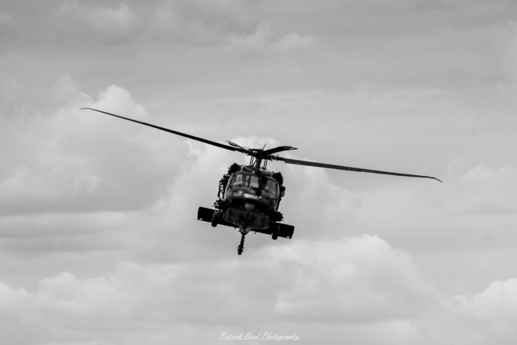 "The Black Hawk helicopter, a versatile and iconic military aircraft, is depicted in a dynamic flying pose against a clear sky. Known for its distinctive twin-engine design, the Black Hawk features a robust fuselage, rotor blades, and a tail rotor that contribute to its agility and stability in flight. The helicopter is painted in a tactical green or black camouflage, often adorned with military markings and insignia. Its capabilities for troop transport, medical evacuation, and logistical support highlight its crucial role in modern military operations. The scene captures the powerful presence of the Black Hawk, showcasing its importance in air mobility and combat scenarios."