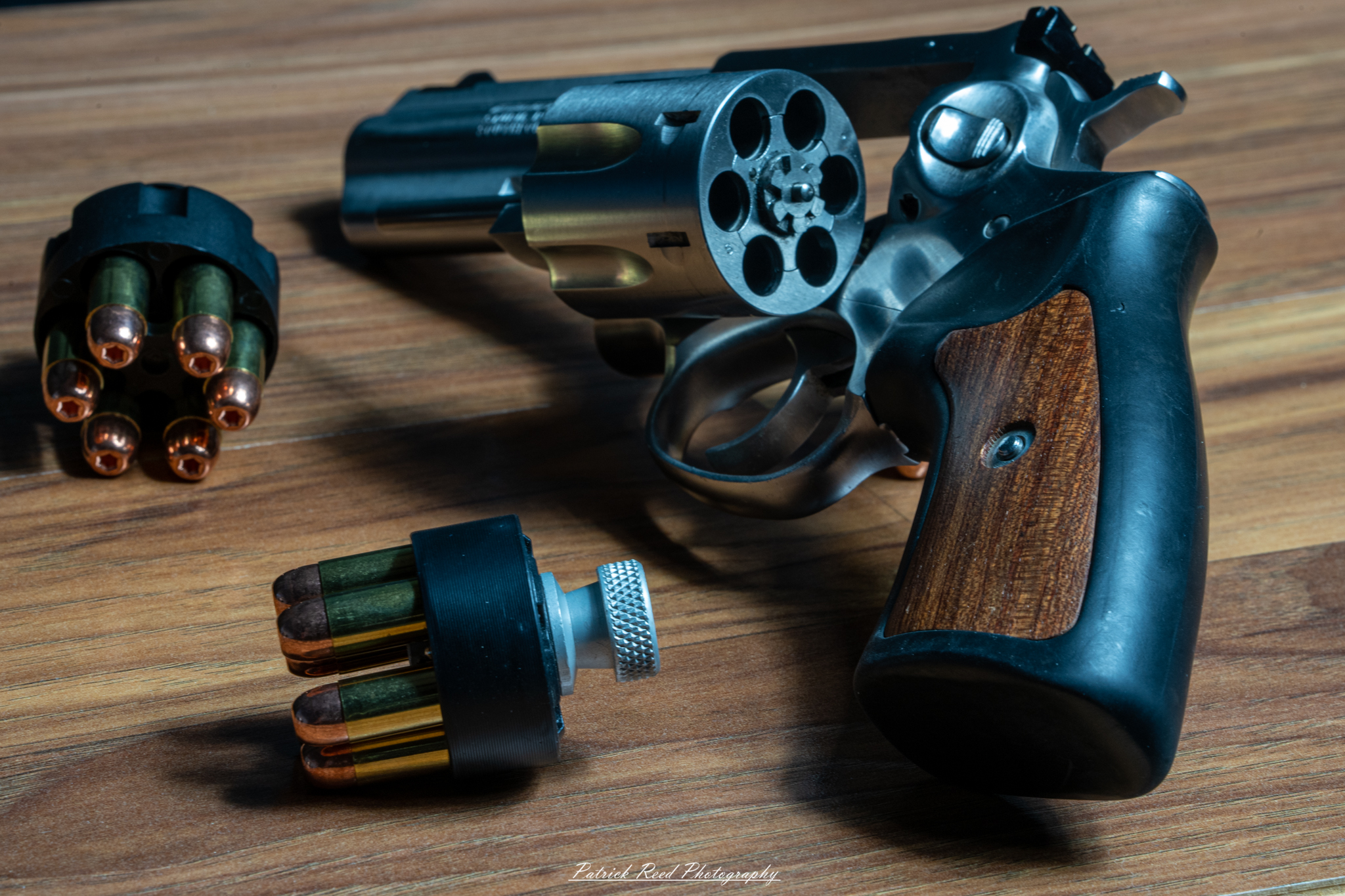 "A Ruger GP100 revolver displayed on a flat surface with two speedloaders placed beside it. The image highlights the revolver's robust and reliable design, with the speedloaders emphasizing the readiness and efficiency associated with this classic firearm setup."