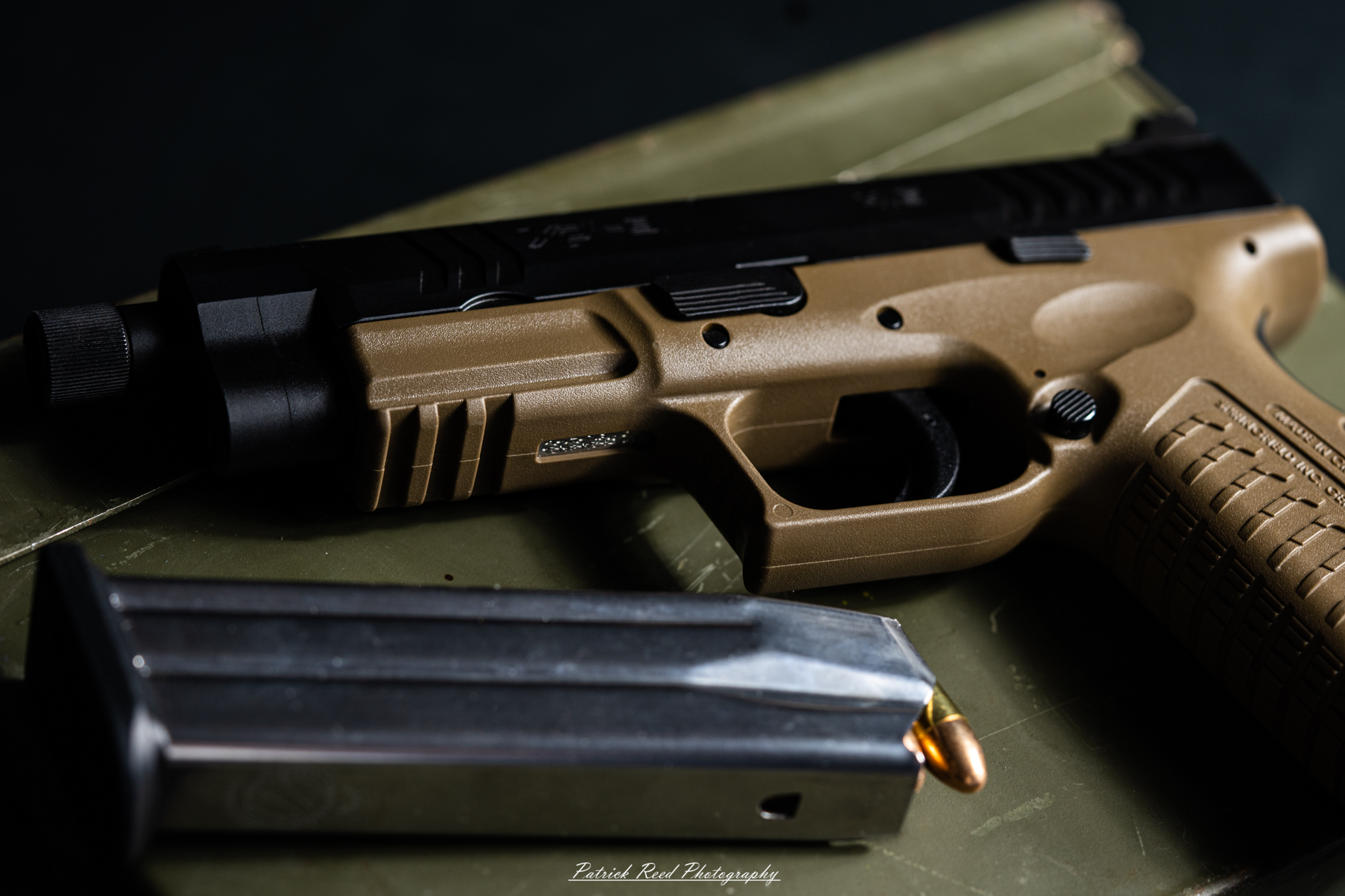 "A Springfield Armory XD-M pistol resting on top of an ammo can, showcasing a rugged and practical setting. The dark, metallic surface of the ammo can contrasts with the sleek design of the firearm, highlighting its readiness for action and the practicality of the setup."