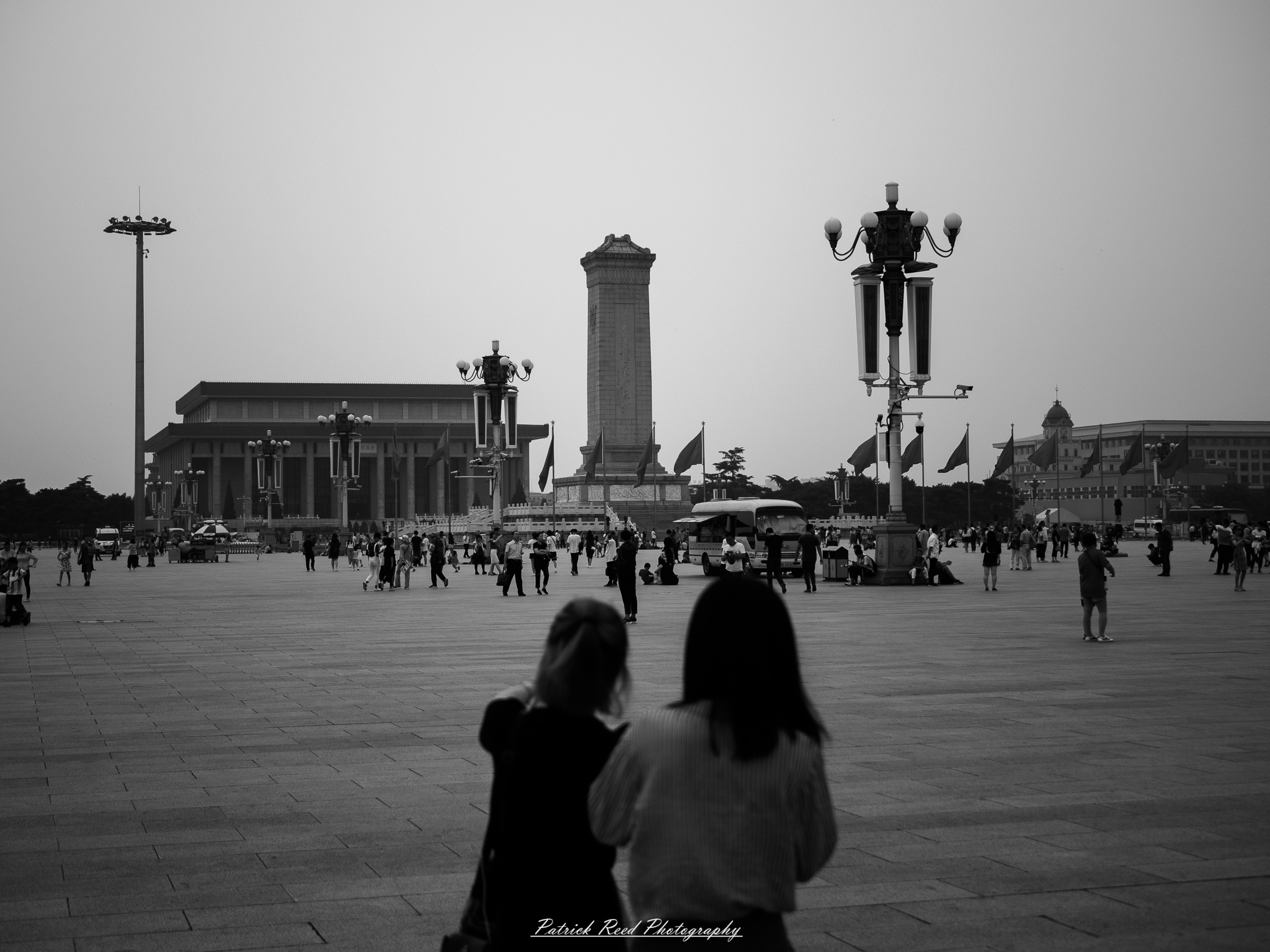 A series of noir-style street photography scenes set in Beijing, China, at night. The rain-slicked alleys and streets reflect the dim glow of neon signs from small shops, tea houses, and street vendors. Silhouettes of people walking under umbrellas or riding bicycles disappear into the misty night. Traditional hutong architecture with tiled roofs and red lanterns contrasts with modern high-rise buildings and glowing billboards in the distance. The interplay of deep shadows and warm artificial lights creates a cinematic, moody atmosphere, capturing the essence of noir storytelling in the heart of the city.
