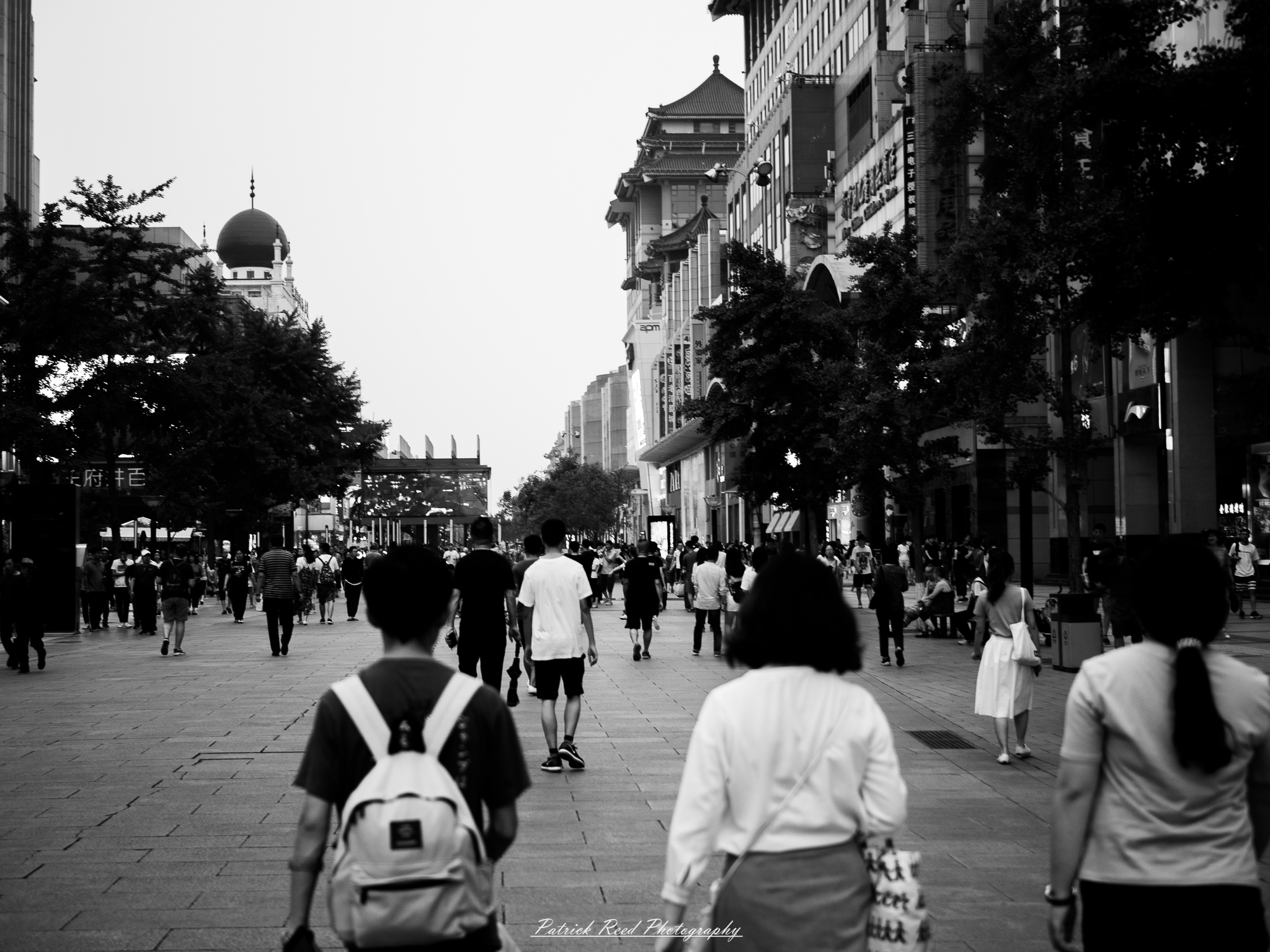 A series of noir-style street photography scenes set in Beijing, China, at night. The rain-slicked alleys and streets reflect the dim glow of neon signs from small shops, tea houses, and street vendors. Silhouettes of people walking under umbrellas or riding bicycles disappear into the misty night. Traditional hutong architecture with tiled roofs and red lanterns contrasts with modern high-rise buildings and glowing billboards in the distance. The interplay of deep shadows and warm artificial lights creates a cinematic, moody atmosphere, capturing the essence of noir storytelling in the heart of the city.