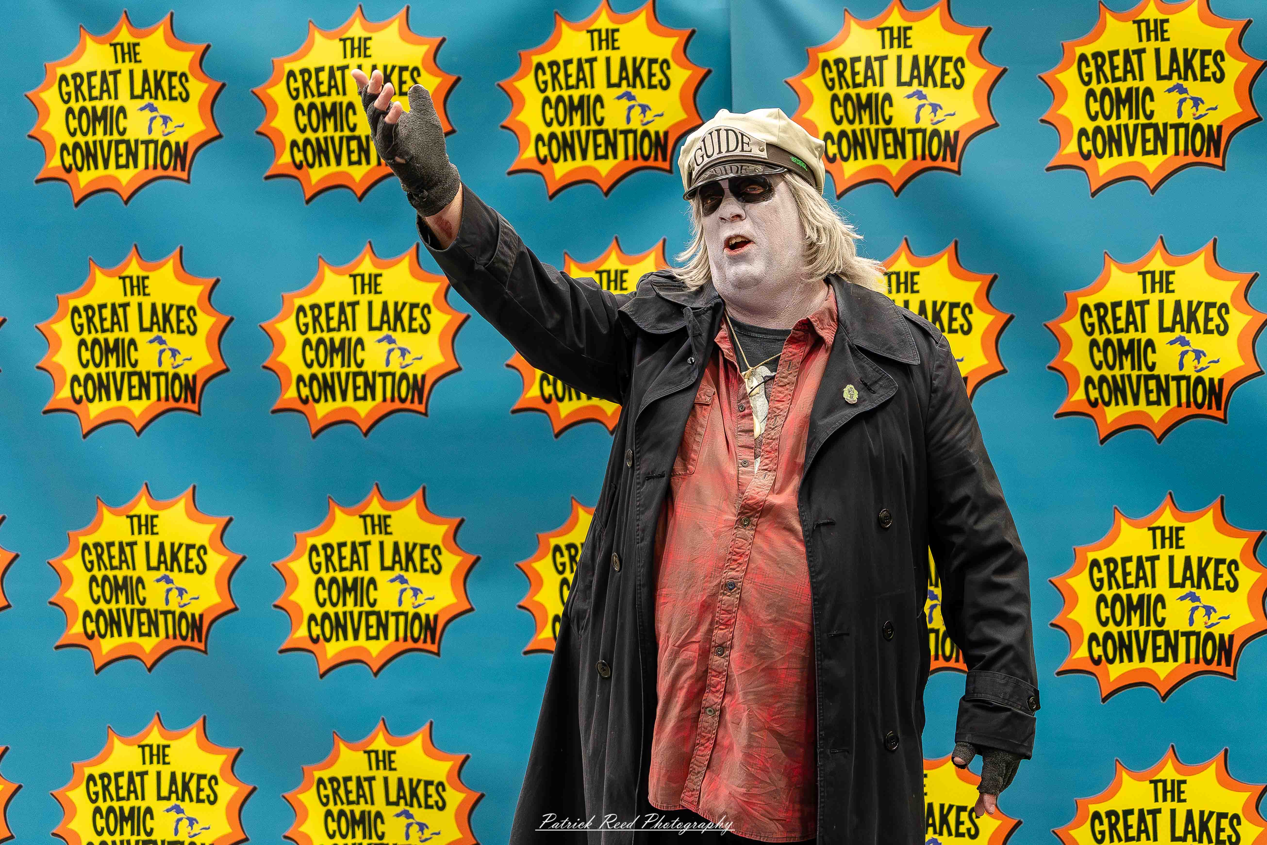 Great Lakes Comic Con 16 Alt text: A group of cosplayers posing on stage at the Great Lakes Comic Con cosplay contest, dressed as various characters from comics, anime, and video games. The audience watches from below as the participants show off their detailed costumes under bright stage lights.