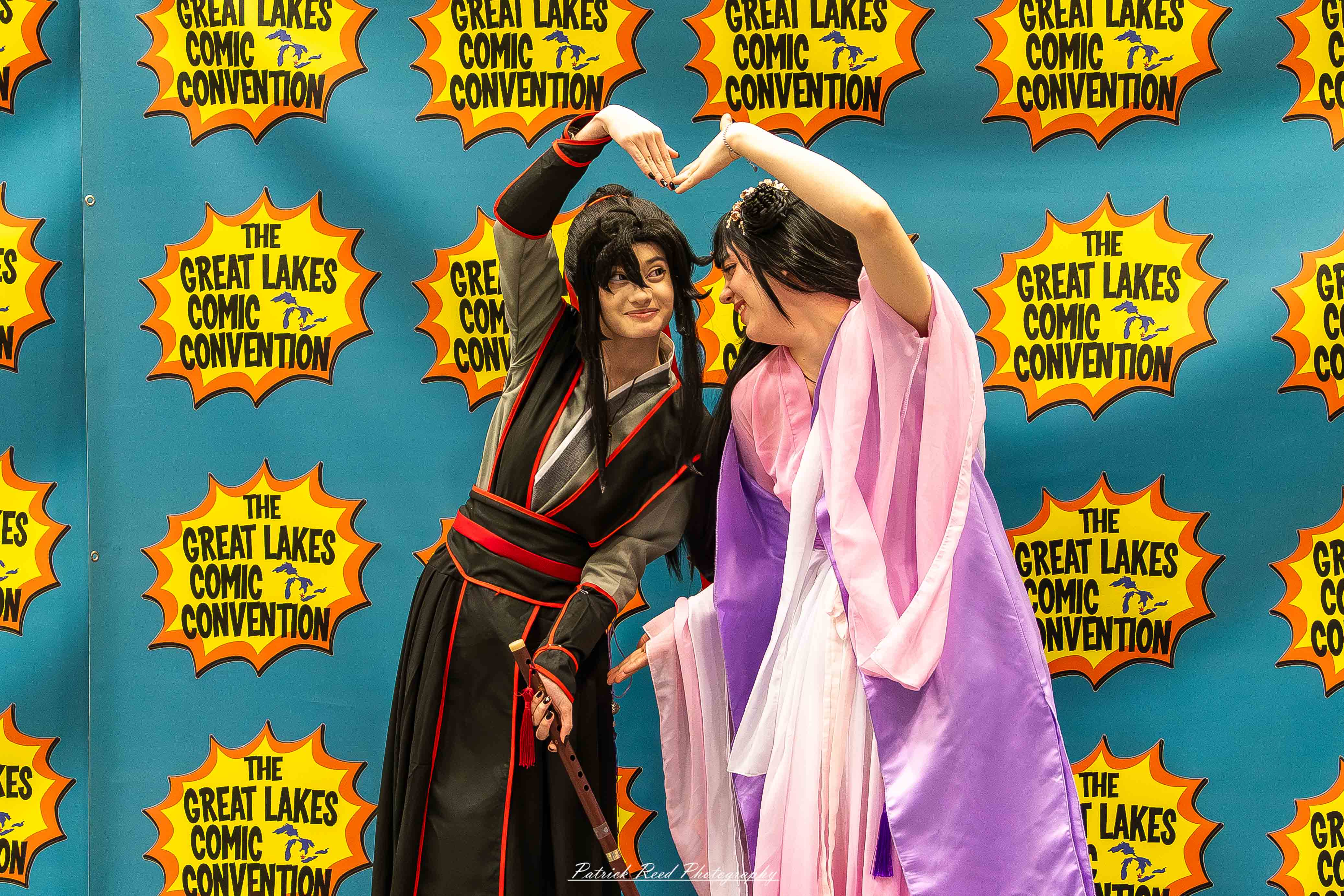 Great Lakes Comic Con 18 Alt text: A group of cosplayers posing on stage at the Great Lakes Comic Con cosplay contest, dressed as various characters from comics, anime, and video games. The audience watches from below as the participants show off their detailed costumes under bright stage lights.