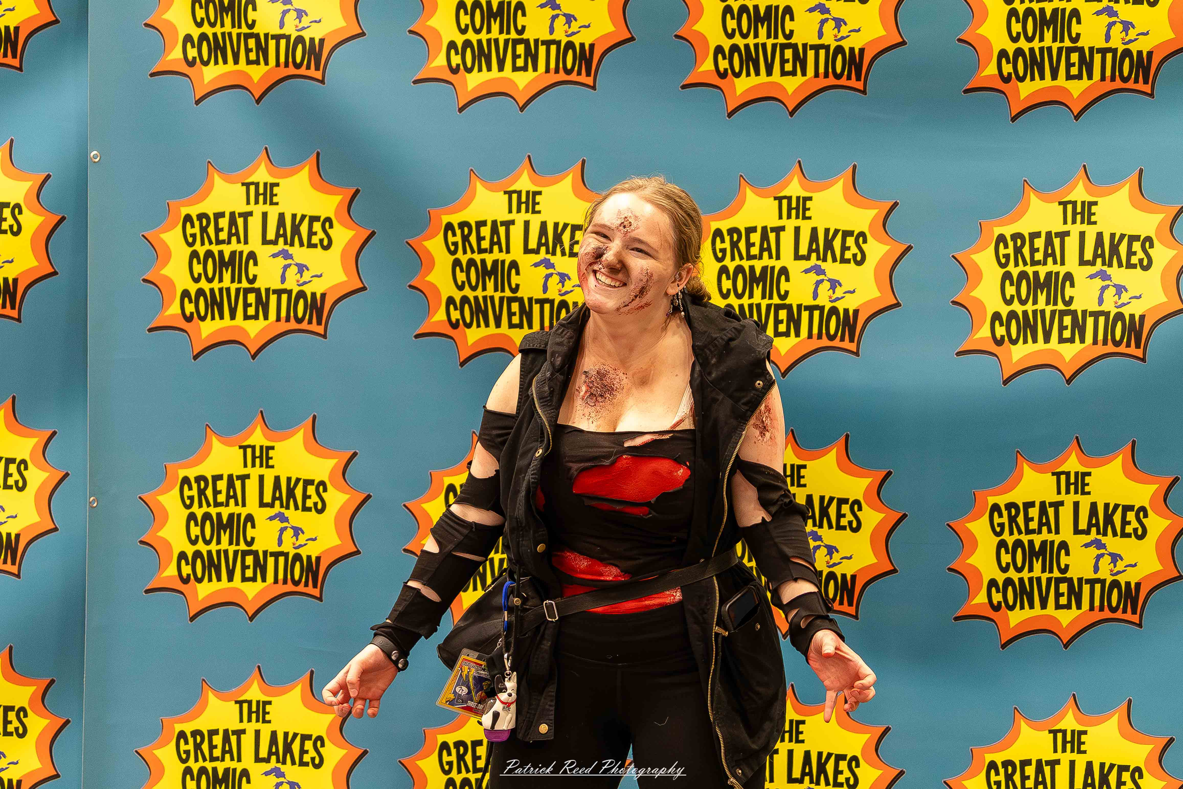 Great Lakes Comic Con 20 Alt text: A group of cosplayers posing on stage at the Great Lakes Comic Con cosplay contest, dressed as various characters from comics, anime, and video games. The audience watches from below as the participants show off their detailed costumes under bright stage lights.