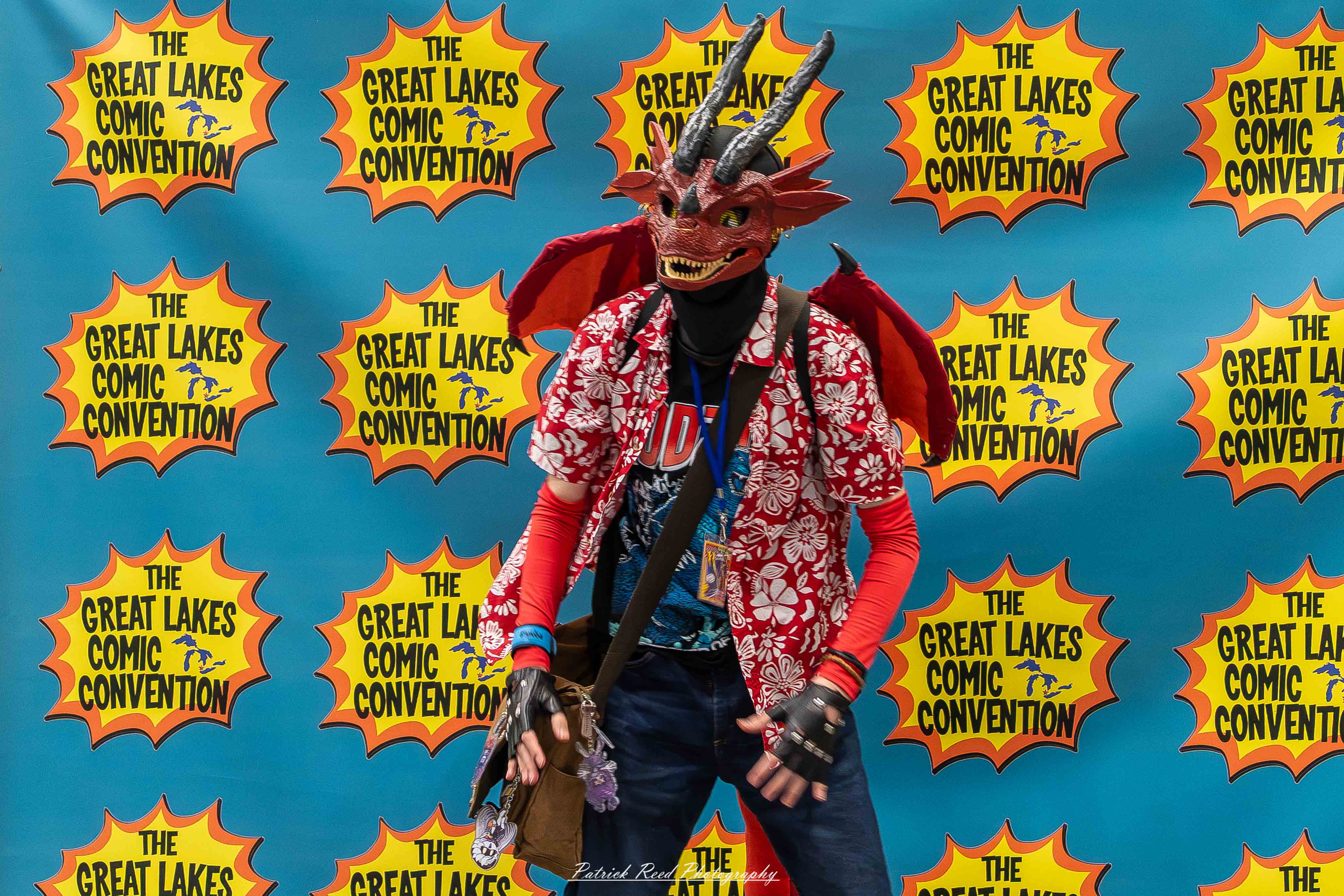 Great Lakes Comic Con 21 Alt text: A group of cosplayers posing on stage at the Great Lakes Comic Con cosplay contest, dressed as various characters from comics, anime, and video games. The audience watches from below as the participants show off their detailed costumes under bright stage lights.