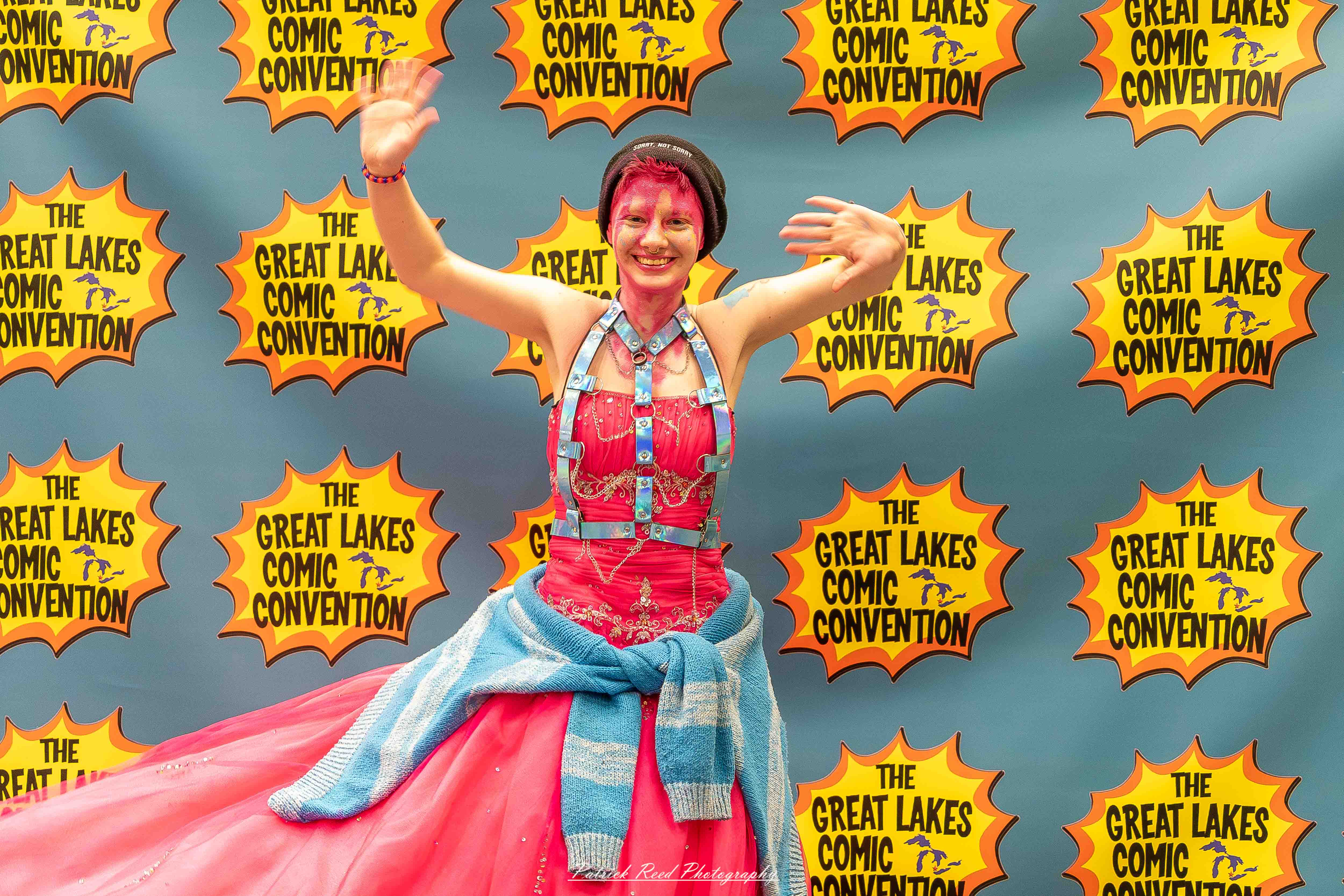 Great Lakes Comic Con 23 Alt text: A group of cosplayers posing on stage at the Great Lakes Comic Con cosplay contest, dressed as various characters from comics, anime, and video games. The audience watches from below as the participants show off their detailed costumes under bright stage lights.