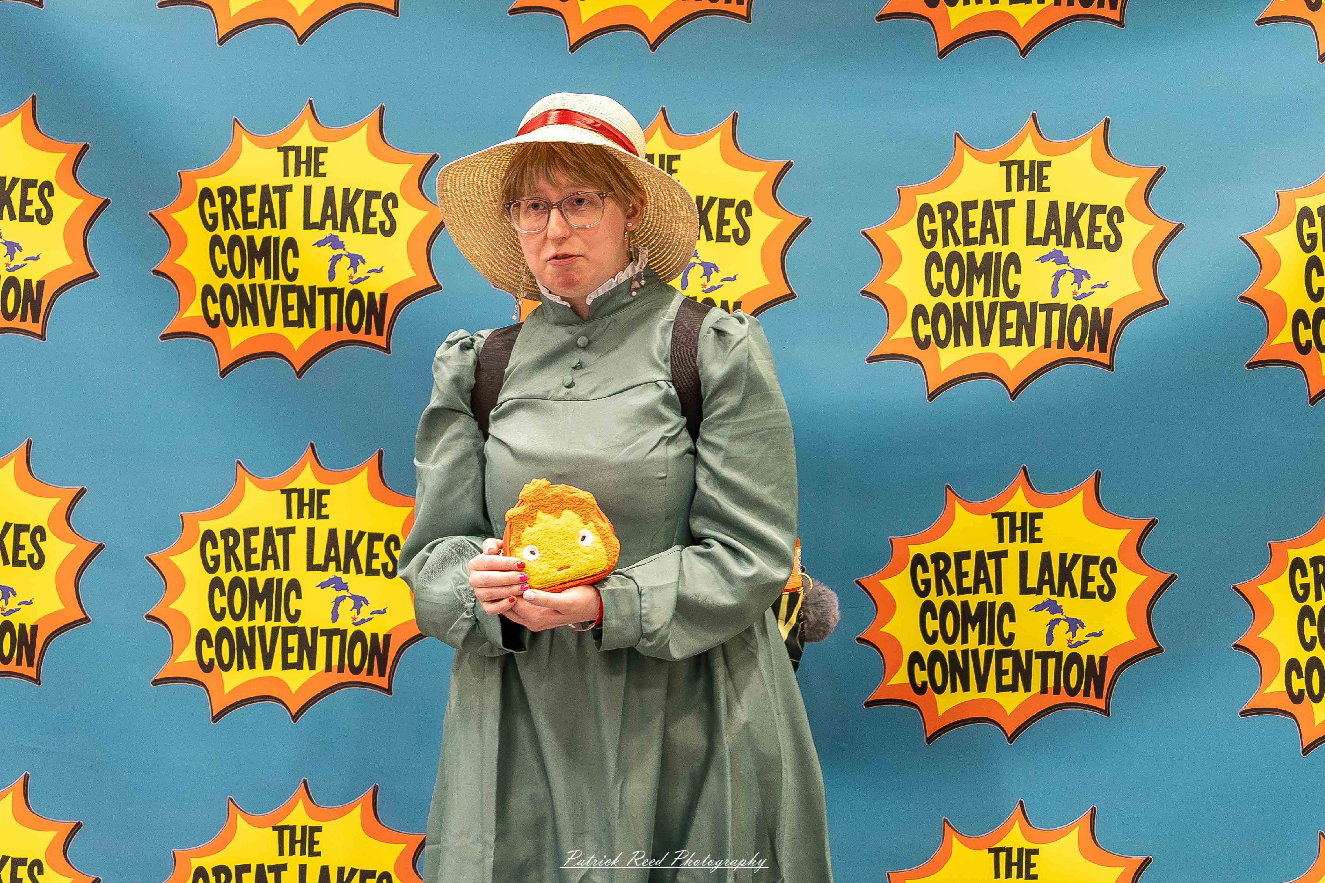 Great Lakes Comic Con 24 Alt text: A group of cosplayers posing on stage at the Great Lakes Comic Con cosplay contest, dressed as various characters from comics, anime, and video games. The audience watches from below as the participants show off their detailed costumes under bright stage lights.
