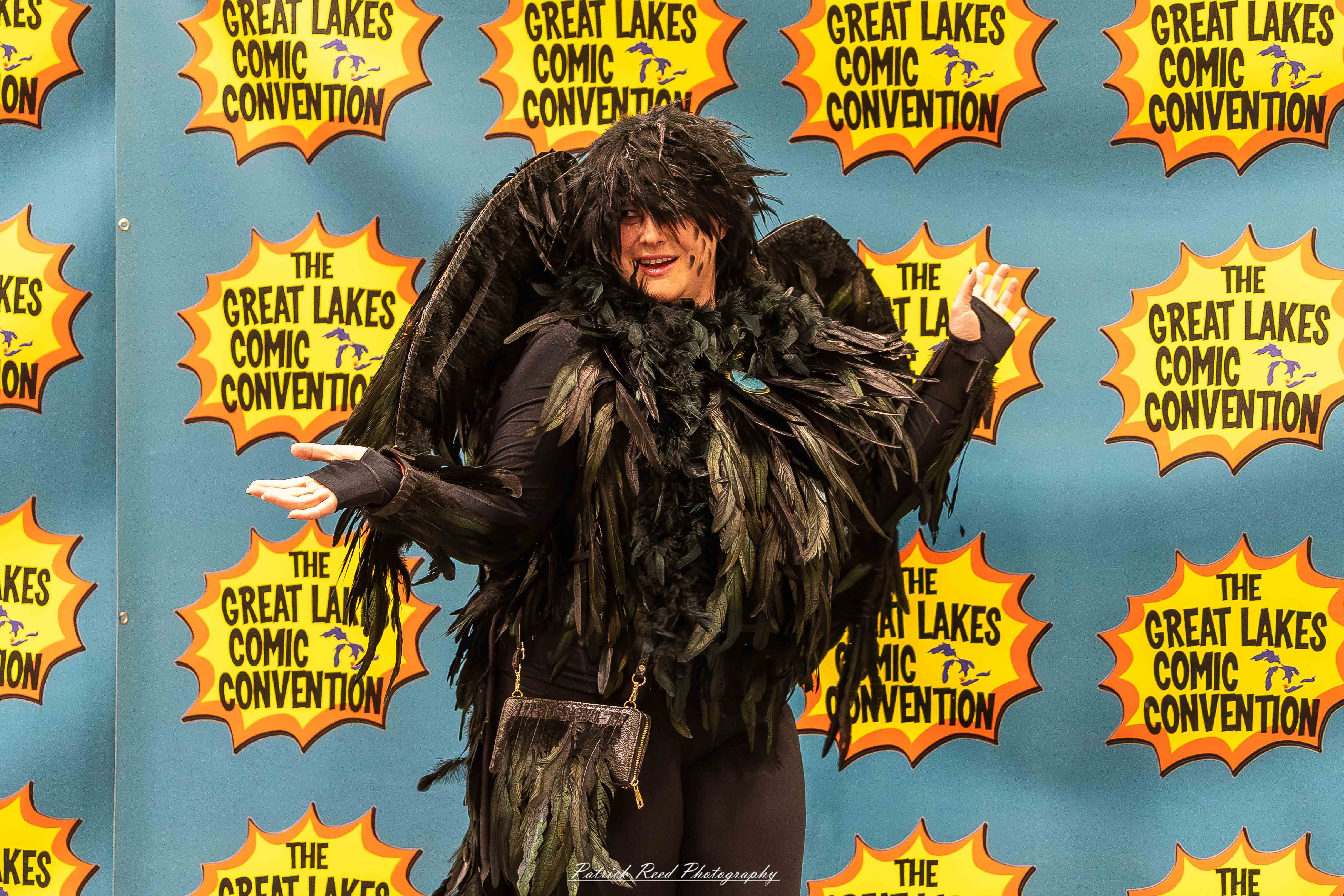 Great Lakes Comic Con 25 Alt text: A group of cosplayers posing on stage at the Great Lakes Comic Con cosplay contest, dressed as various characters from comics, anime, and video games. The audience watches from below as the participants show off their detailed costumes under bright stage lights.