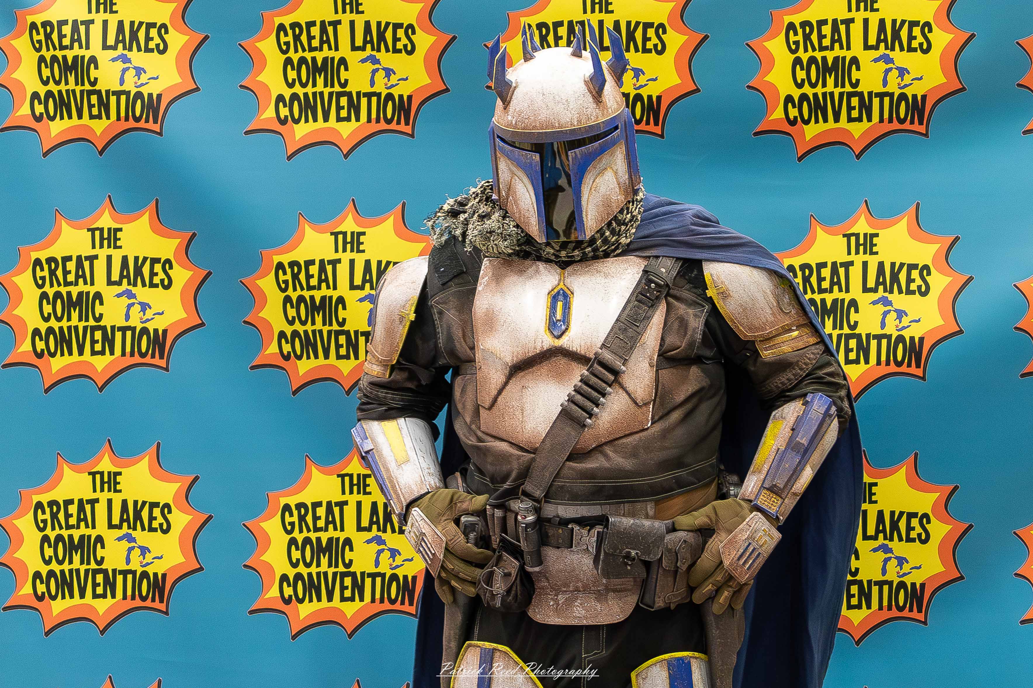 Great Lakes Comic Con 31 Alt text: A group of cosplayers posing on stage at the Great Lakes Comic Con cosplay contest, dressed as various characters from comics, anime, and video games. The audience watches from below as the participants show off their detailed costumes under bright stage lights.