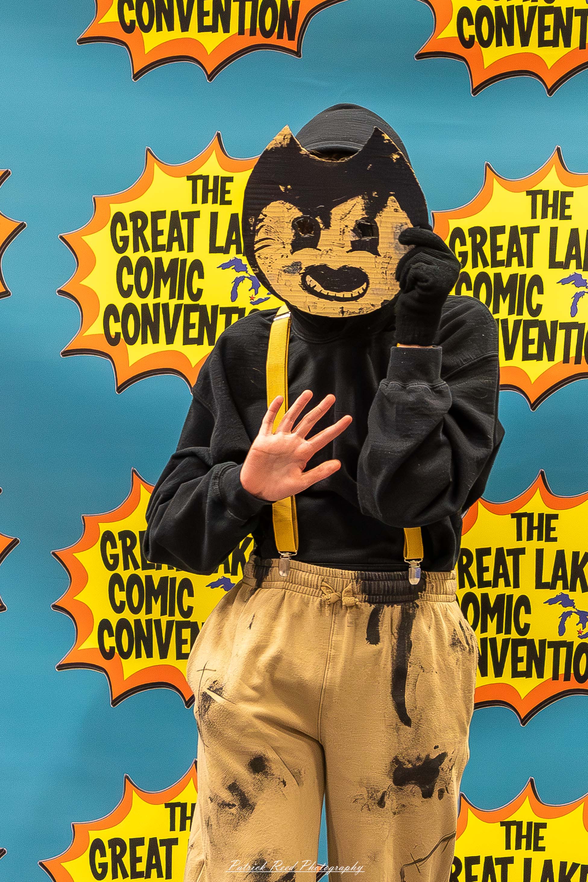 Great Lakes Comic Con 32 Alt text: A group of cosplayers posing on stage at the Great Lakes Comic Con cosplay contest, dressed as various characters from comics, anime, and video games. The audience watches from below as the participants show off their detailed costumes under bright stage lights.