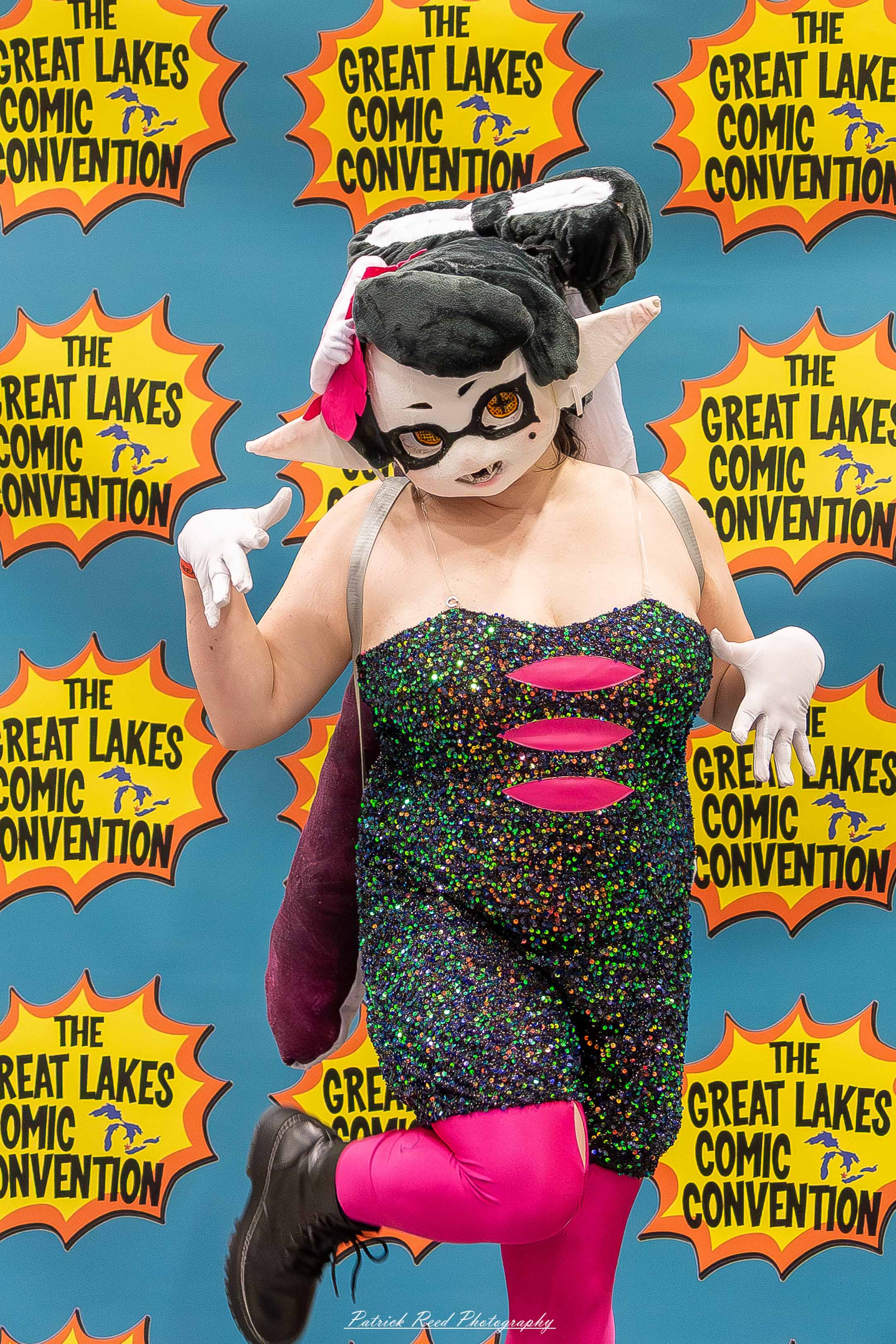 Great Lakes Comic Con 33 Alt text: A group of cosplayers posing on stage at the Great Lakes Comic Con cosplay contest, dressed as various characters from comics, anime, and video games. The audience watches from below as the participants show off their detailed costumes under bright stage lights.