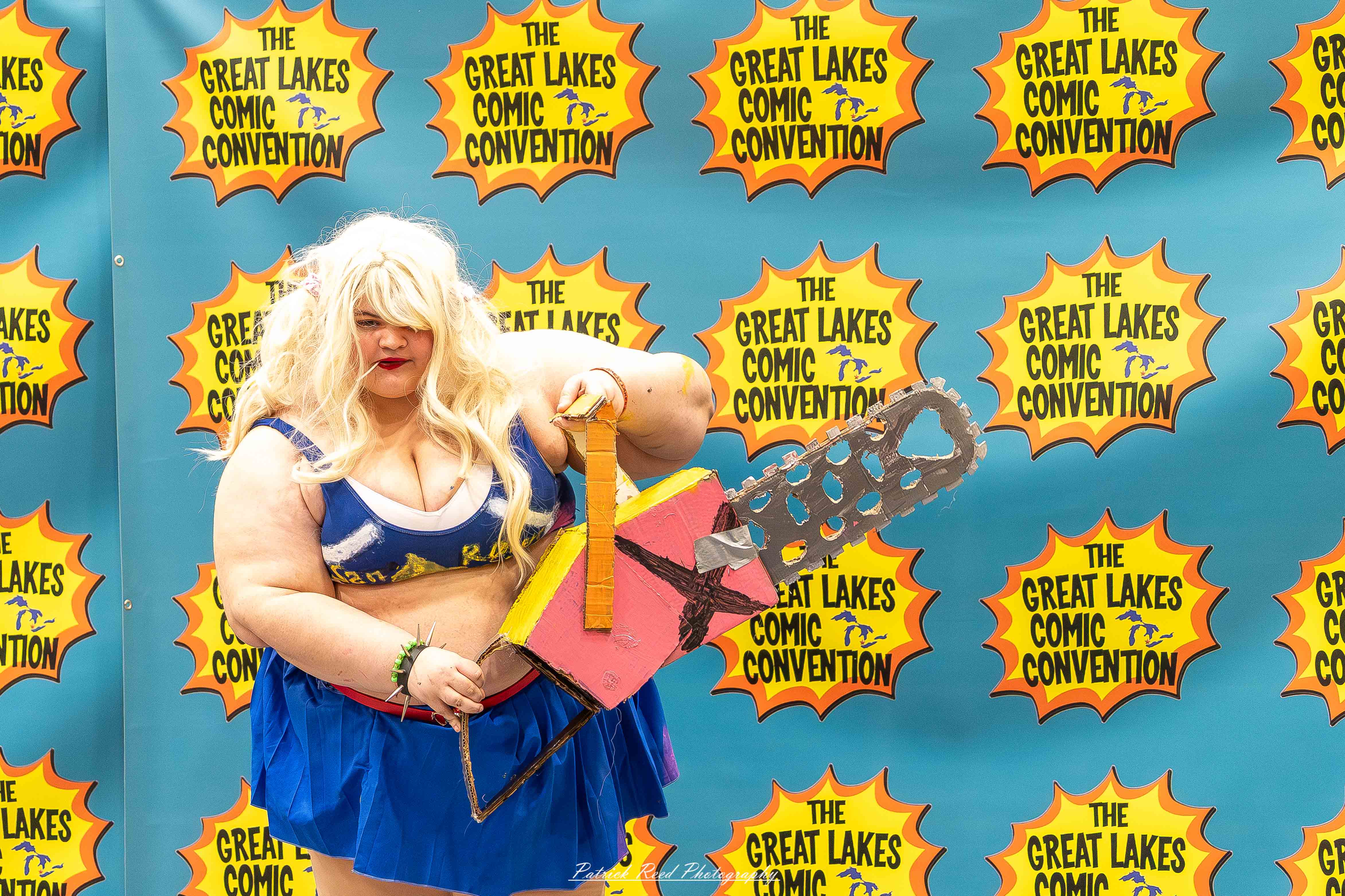 Great Lakes Comic Con 35 Alt text: A group of cosplayers posing on stage at the Great Lakes Comic Con cosplay contest, dressed as various characters from comics, anime, and video games. The audience watches from below as the participants show off their detailed costumes under bright stage lights.