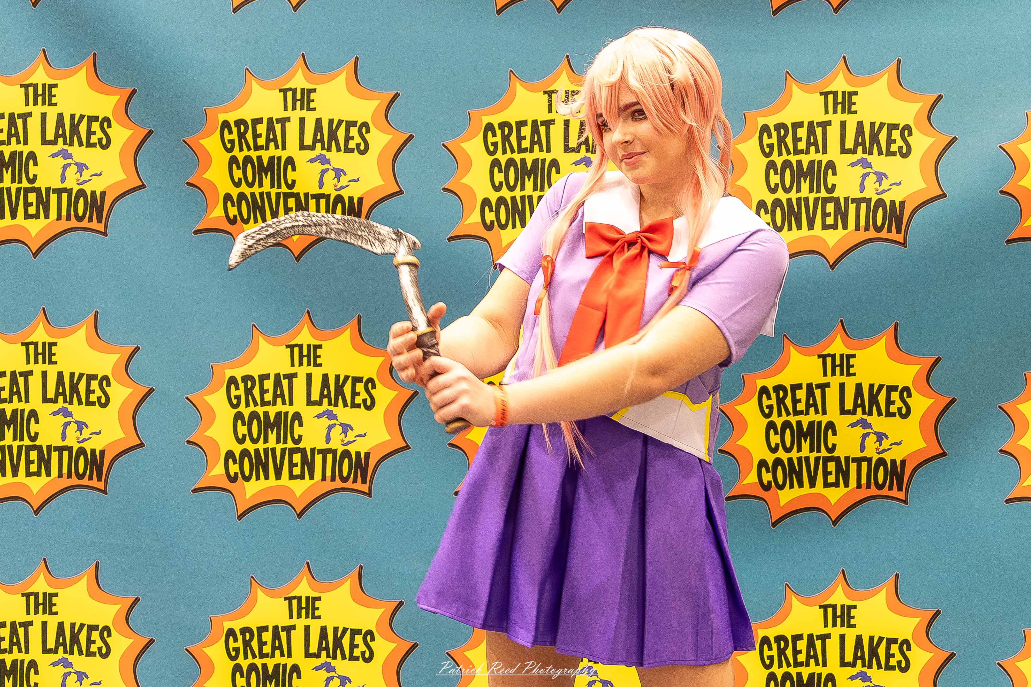 Great Lakes Comic Con 39 Alt text: A group of cosplayers posing on stage at the Great Lakes Comic Con cosplay contest, dressed as various characters from comics, anime, and video games. The audience watches from below as the participants show off their detailed costumes under bright stage lights.