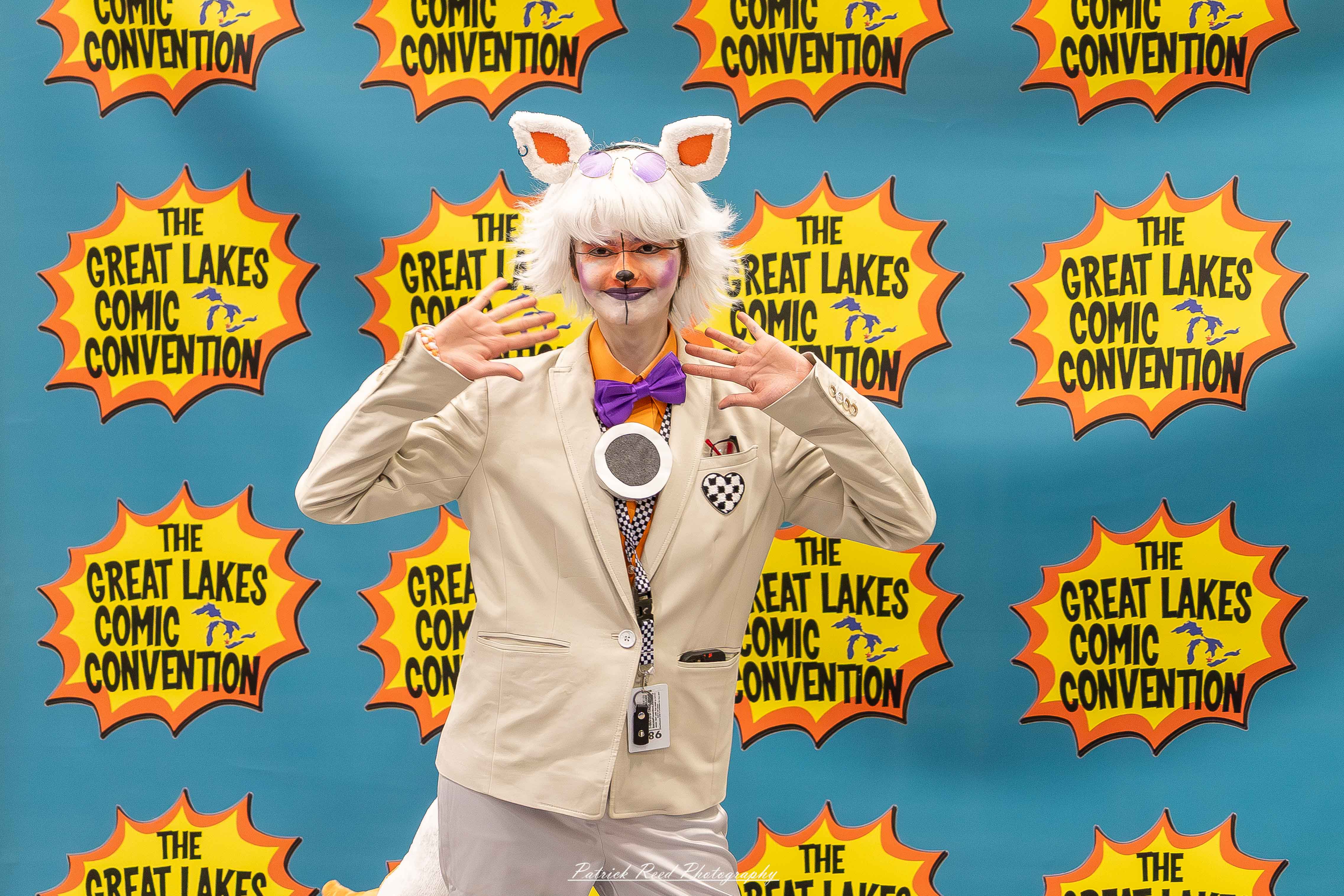Great Lakes Comic Con 40 Alt text: A group of cosplayers posing on stage at the Great Lakes Comic Con cosplay contest, dressed as various characters from comics, anime, and video games. The audience watches from below as the participants show off their detailed costumes under bright stage lights.
