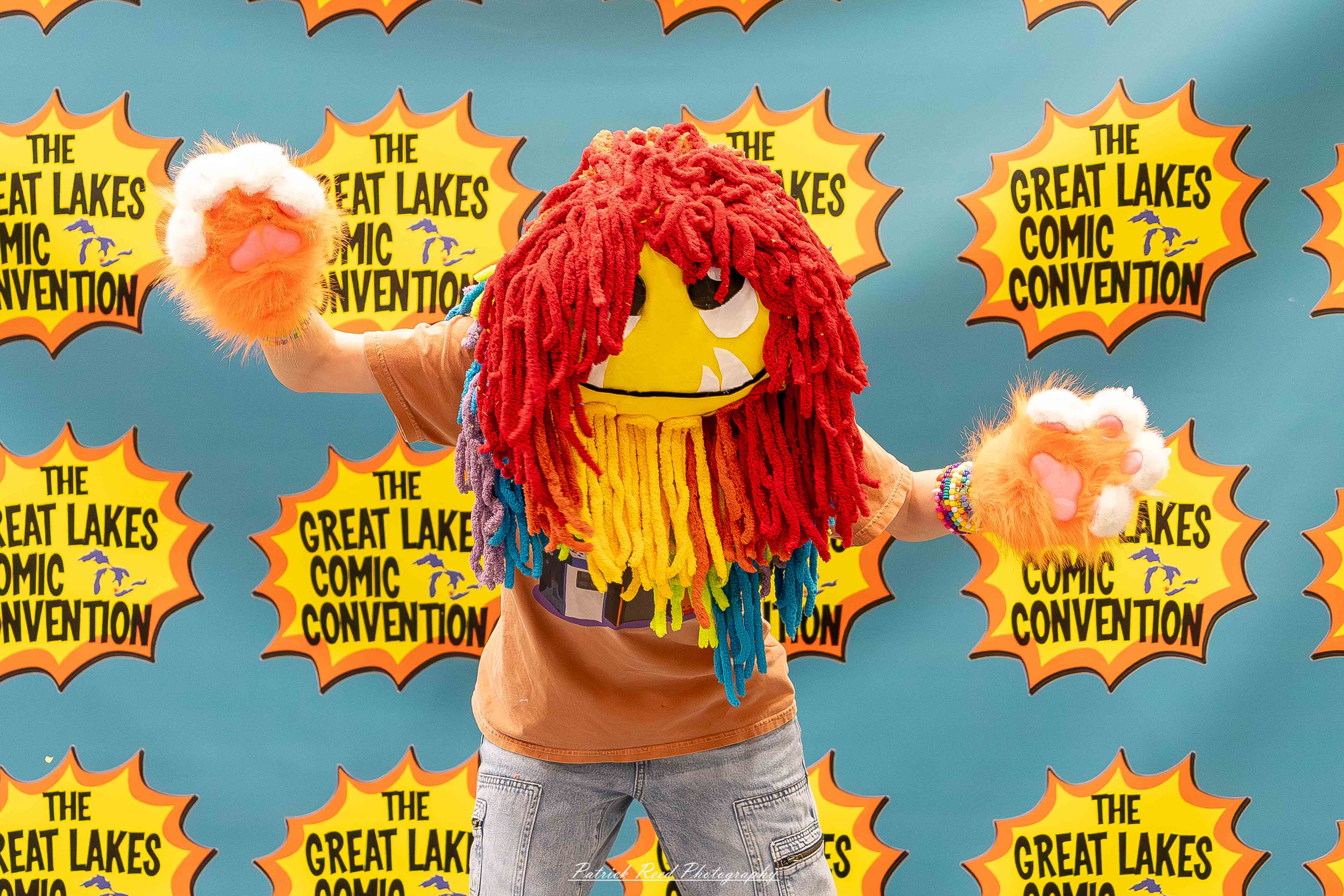 Great Lakes Comic Con 42 Alt text: A group of cosplayers posing on stage at the Great Lakes Comic Con cosplay contest, dressed as various characters from comics, anime, and video games. The audience watches from below as the participants show off their detailed costumes under bright stage lights.