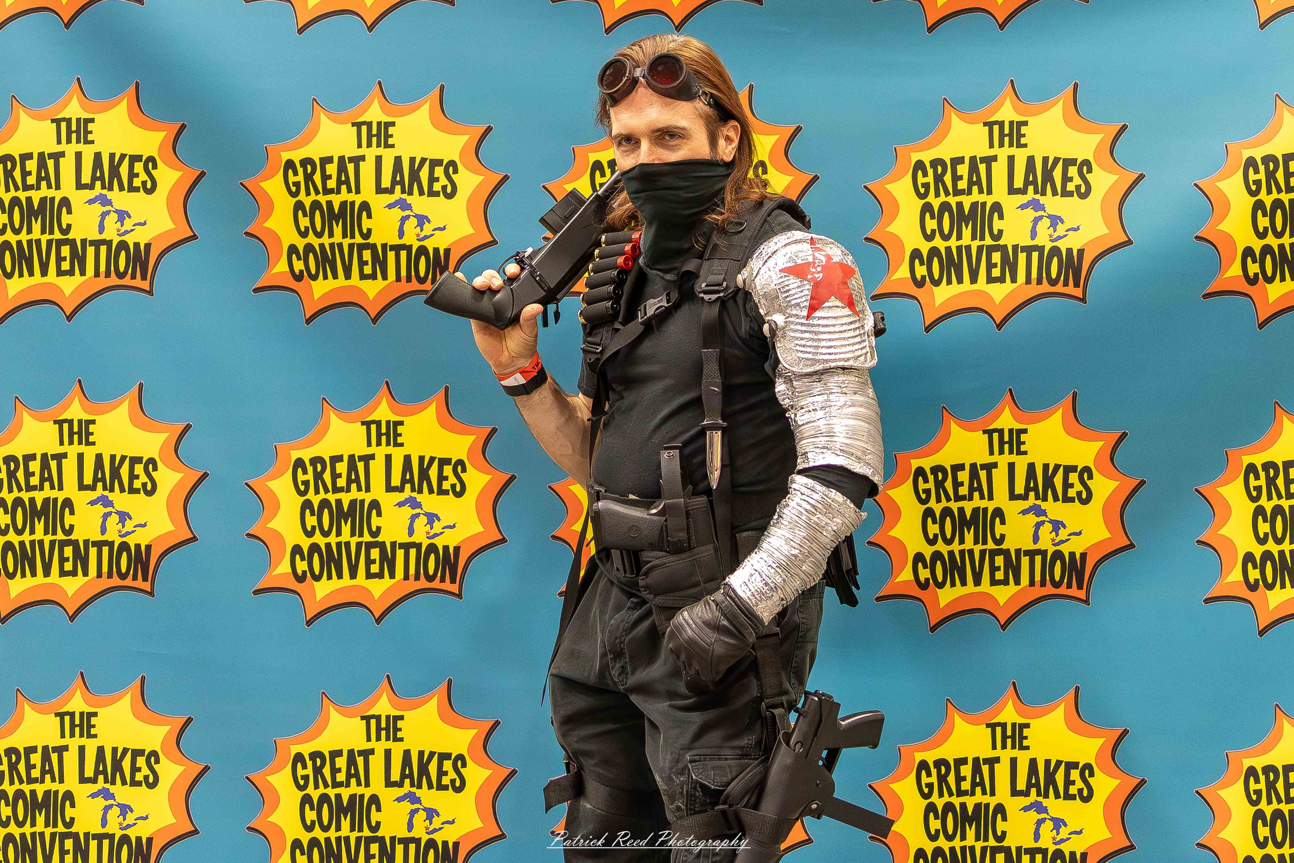 Great Lakes Comic Con 44 Alt text: A group of cosplayers posing on stage at the Great Lakes Comic Con cosplay contest, dressed as various characters from comics, anime, and video games. The audience watches from below as the participants show off their detailed costumes under bright stage lights.