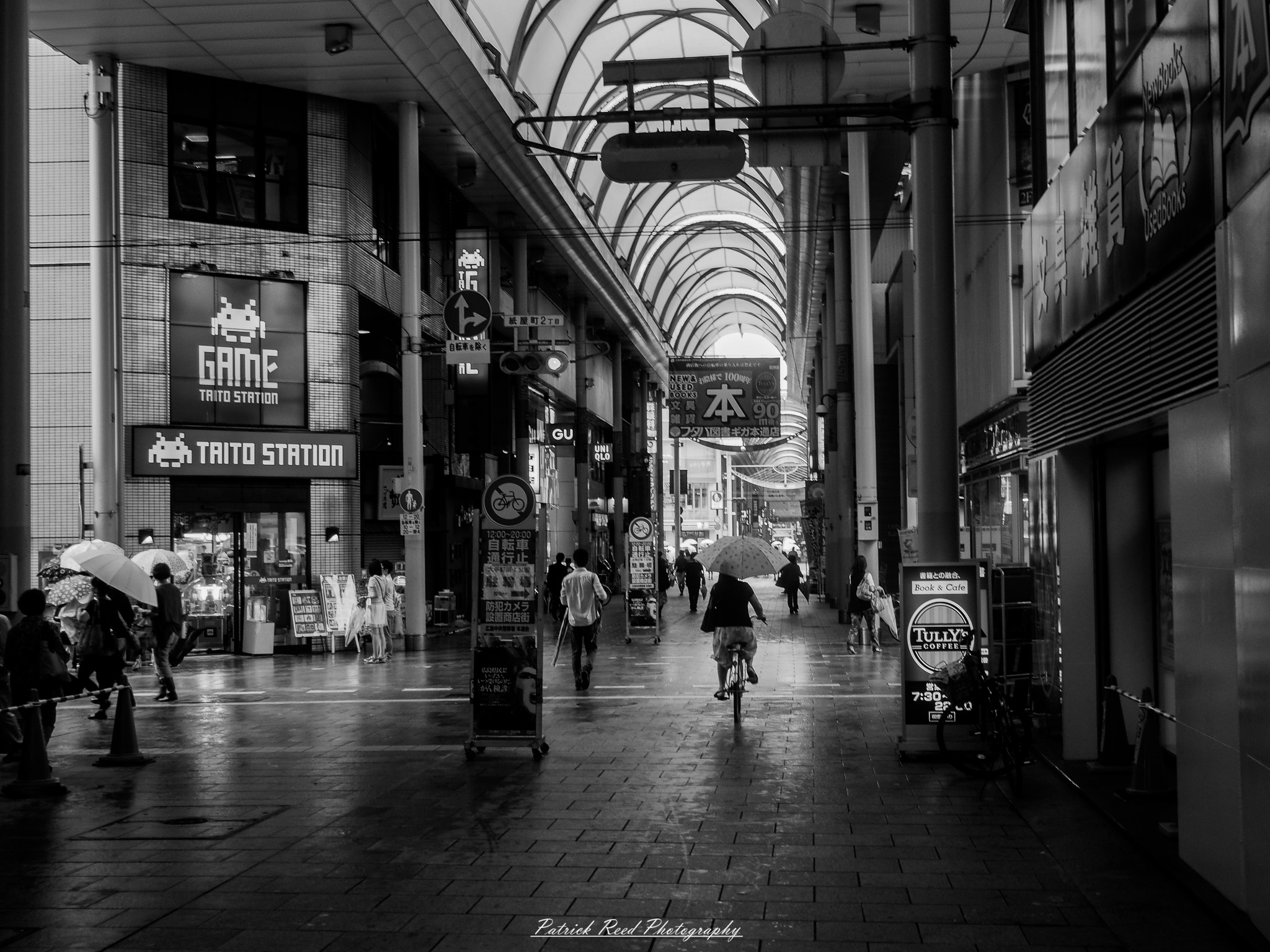 A series of noir-style street photography scenes set in Hiroshima, Japan, at night. The rain-slicked streets and narrow alleys reflect the soft glow of neon signs from izakayas, small shops, and vending machines. Silhouettes of people walking under umbrellas move through the misty atmosphere, their shadows stretching across the pavement. Traditional Japanese architecture, such as wooden facades and noren curtains, blends with modern urban elements like glowing billboards and bicycles parked along dimly lit sidewalks. The moody lighting, deep contrasts, and quiet yet cinematic ambiance evoke a sense of mystery and nostalgia, capturing the noir aesthetic in a contemporary Japanese cityscape.