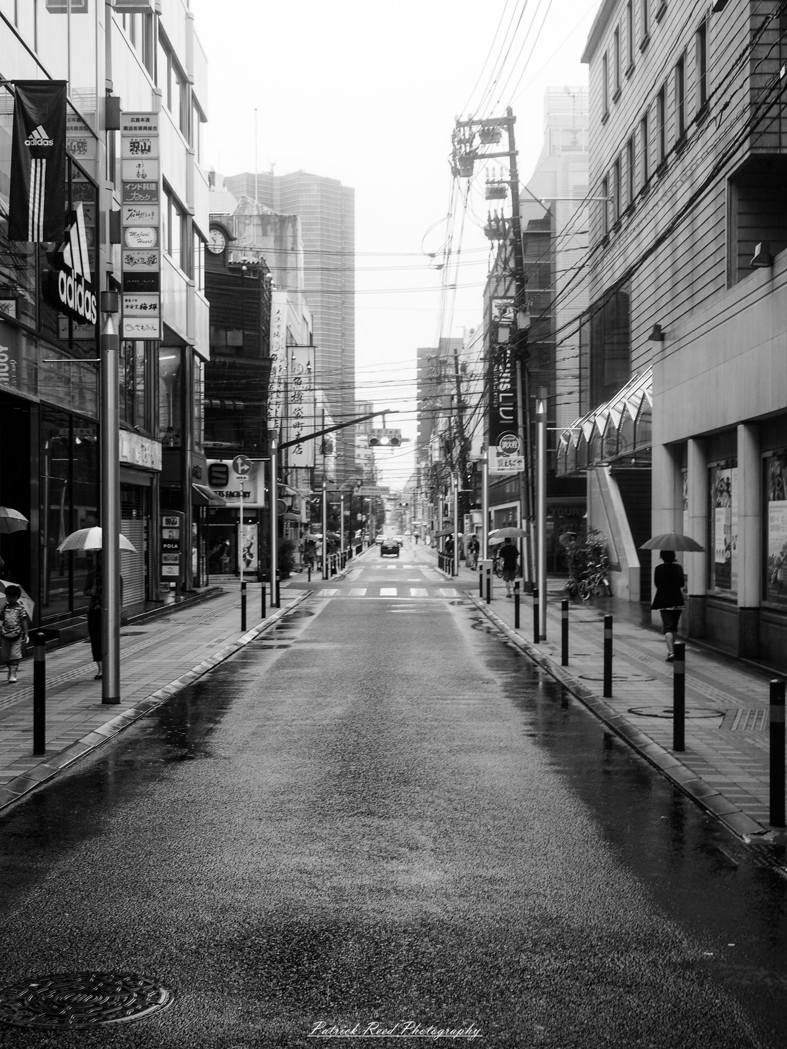 A series of noir-style street photography scenes set in Hiroshima, Japan, at night. The rain-slicked streets and narrow alleys reflect the soft glow of neon signs from izakayas, small shops, and vending machines. Silhouettes of people walking under umbrellas move through the misty atmosphere, their shadows stretching across the pavement. Traditional Japanese architecture, such as wooden facades and noren curtains, blends with modern urban elements like glowing billboards and bicycles parked along dimly lit sidewalks. The moody lighting, deep contrasts, and quiet yet cinematic ambiance evoke a sense of mystery and nostalgia, capturing the noir aesthetic in a contemporary Japanese cityscape.