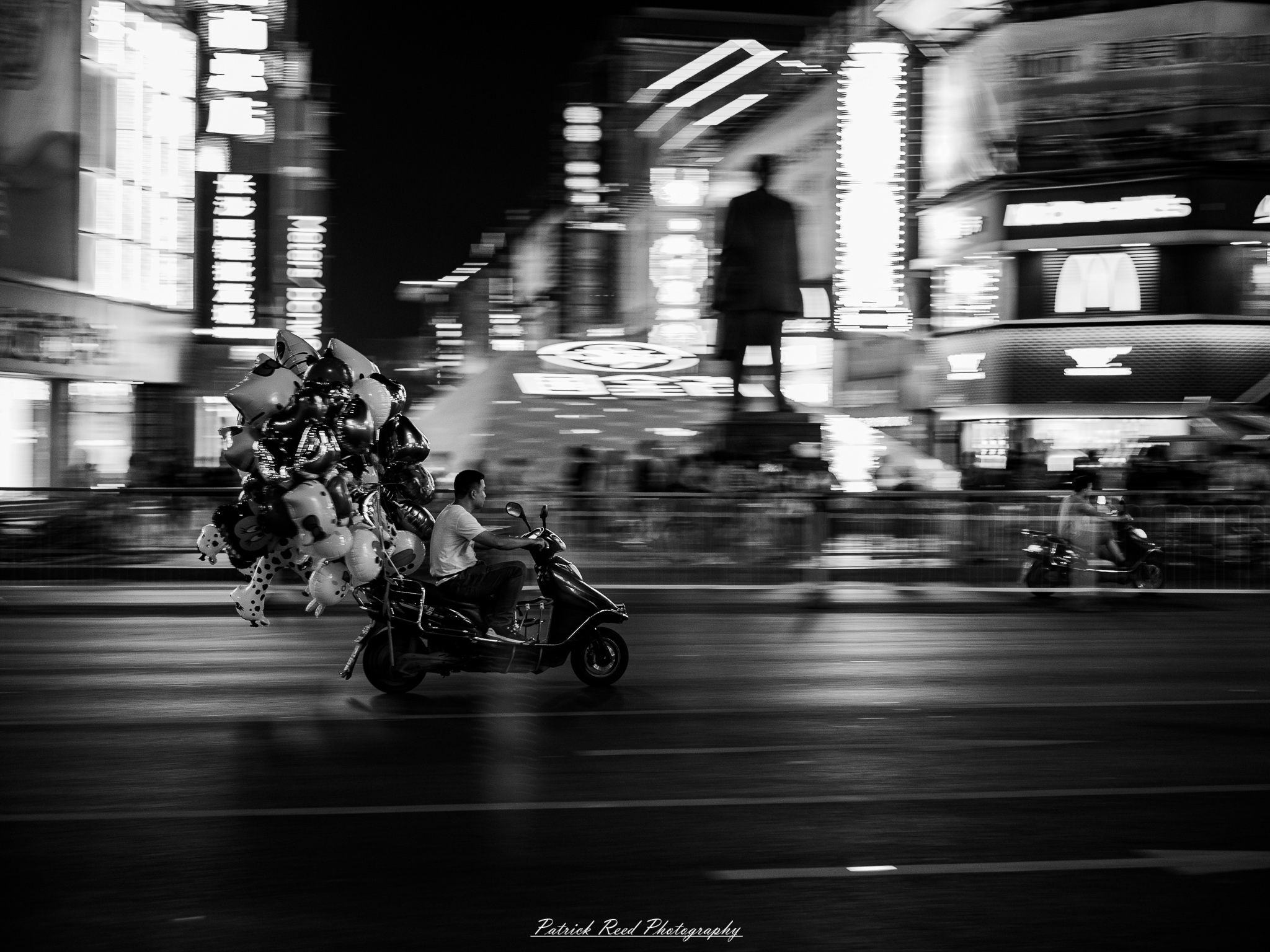 China Scooter 1 A noir-style scene of a Chinese street at night, featuring a rain-soaked pavement reflecting vibrant neon lights from signs and storefronts. A scooter is parked to the side, its silhouette illuminated by the glow of nearby lights. Traditional Chinese architectural elements blend with modern urban surroundings. Silhouettes of people holding umbrellas move through the misty atmosphere, adding an air of mystery. The composition is moody and cinematic, emphasizing the wet reflections and gritty textures.