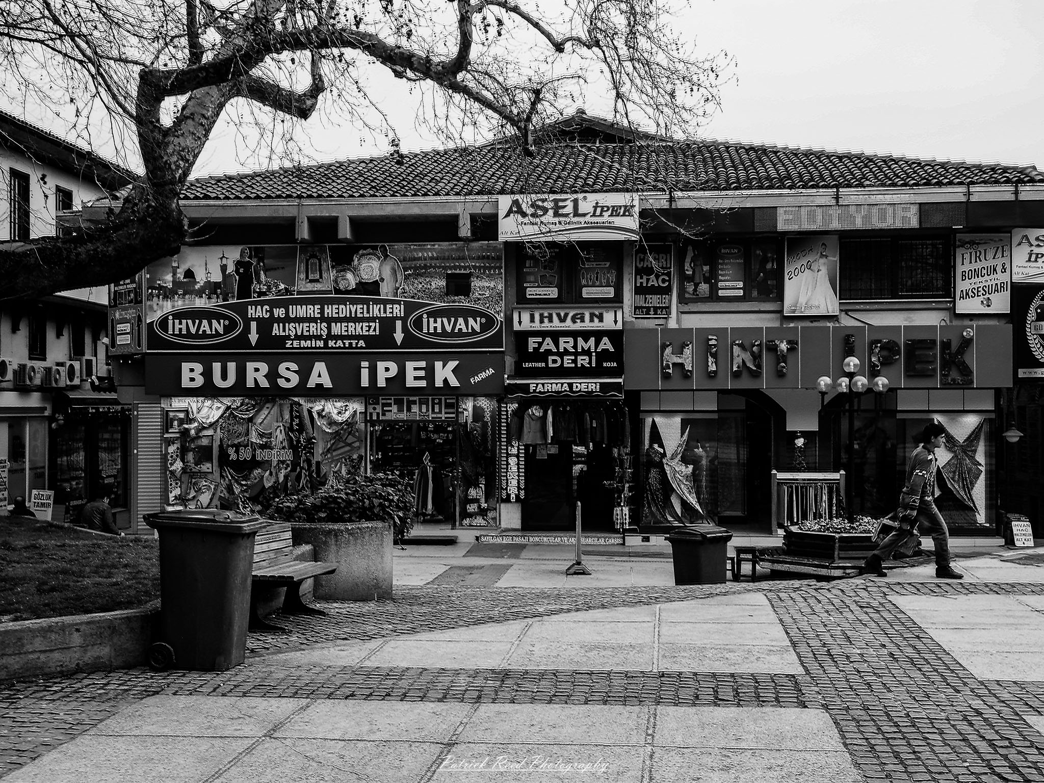 Turkey 2 A series of noir-style street photography scenes set in Istanbul, Turkey, at night. The dimly lit streets and narrow alleys are wet from rain, reflecting the warm glow of streetlights and neon signs. Silhouettes of people walking, some carrying umbrellas, move through the misty atmosphere. The scenes highlight a blend of historical Ottoman architecture, such as arched doorways and intricate stone facades, with modern urban elements like cafes, storefronts, and graffiti. The Bosphorus skyline and glimpses of minarets in the distance add to the cinematic, mysterious ambiance. The overall mood is evocative and steeped in noir storytelling.