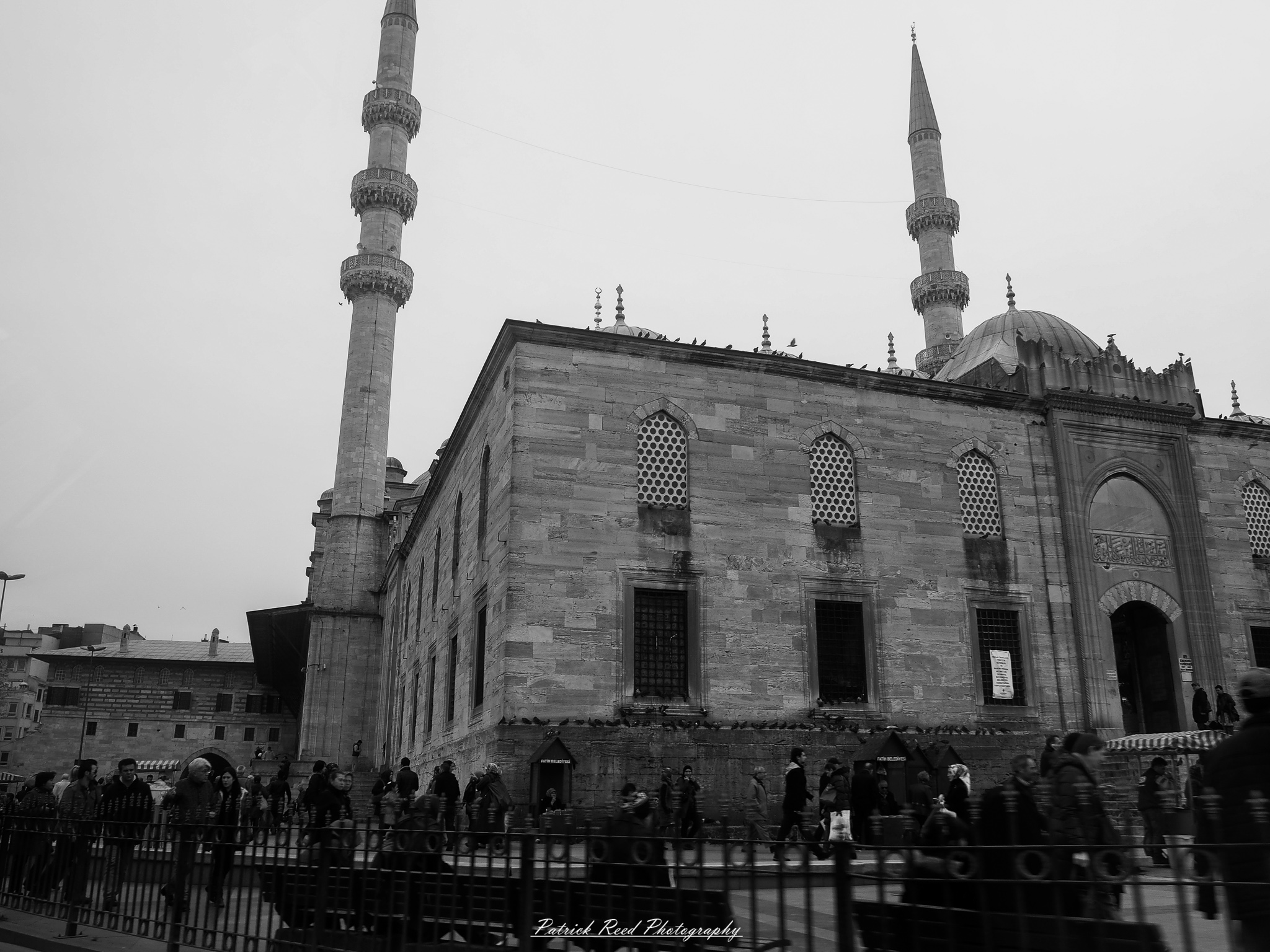 Turkey 5 A series of noir-style street photography scenes set in Istanbul, Turkey, at night. The dimly lit streets and narrow alleys are wet from rain, reflecting the warm glow of streetlights and neon signs. Silhouettes of people walking, some carrying umbrellas, move through the misty atmosphere. The scenes highlight a blend of historical Ottoman architecture, such as arched doorways and intricate stone facades, with modern urban elements like cafes, storefronts, and graffiti. The Bosphorus skyline and glimpses of minarets in the distance add to the cinematic, mysterious ambiance. The overall mood is evocative and steeped in noir storytelling.