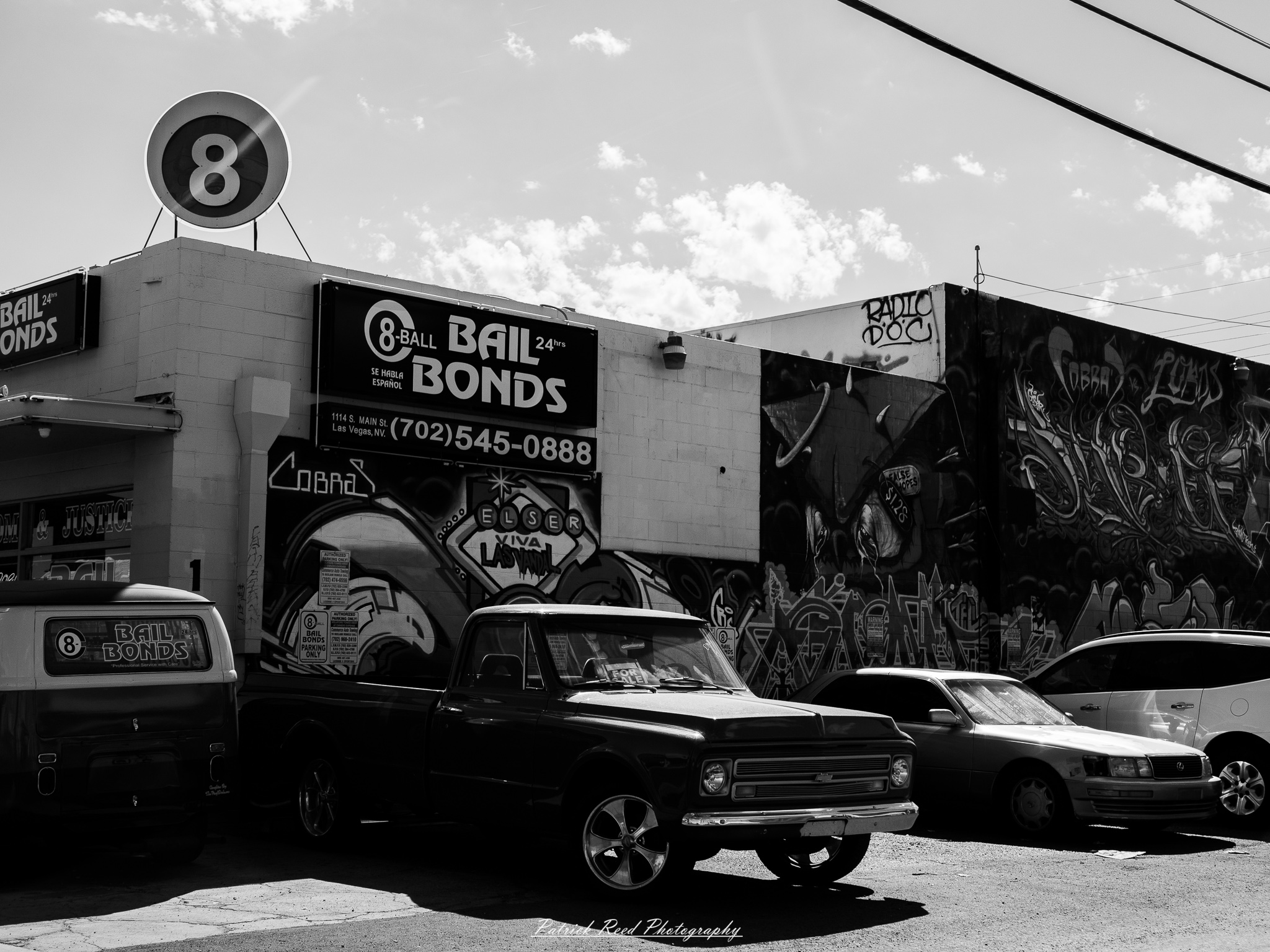 Vegas 11 A series of noir-style street photography scenes set in Las Vegas, Nevada, at night. The rain-slicked streets reflect the vibrant glow of neon signs from casinos, motels, and diners. Silhouettes of people walking under umbrellas or leaning against lampposts add a sense of mystery and intrigue. The scenes capture a mix of classic Vegas landmarks, vintage signage, and gritty back alleys with graffiti and scattered debris. The dramatic lighting emphasizes shadows and contrasts, creating a moody, cinematic ambiance that evokes the essence of noir storytelling in a bustling yet shadowy cityscape.