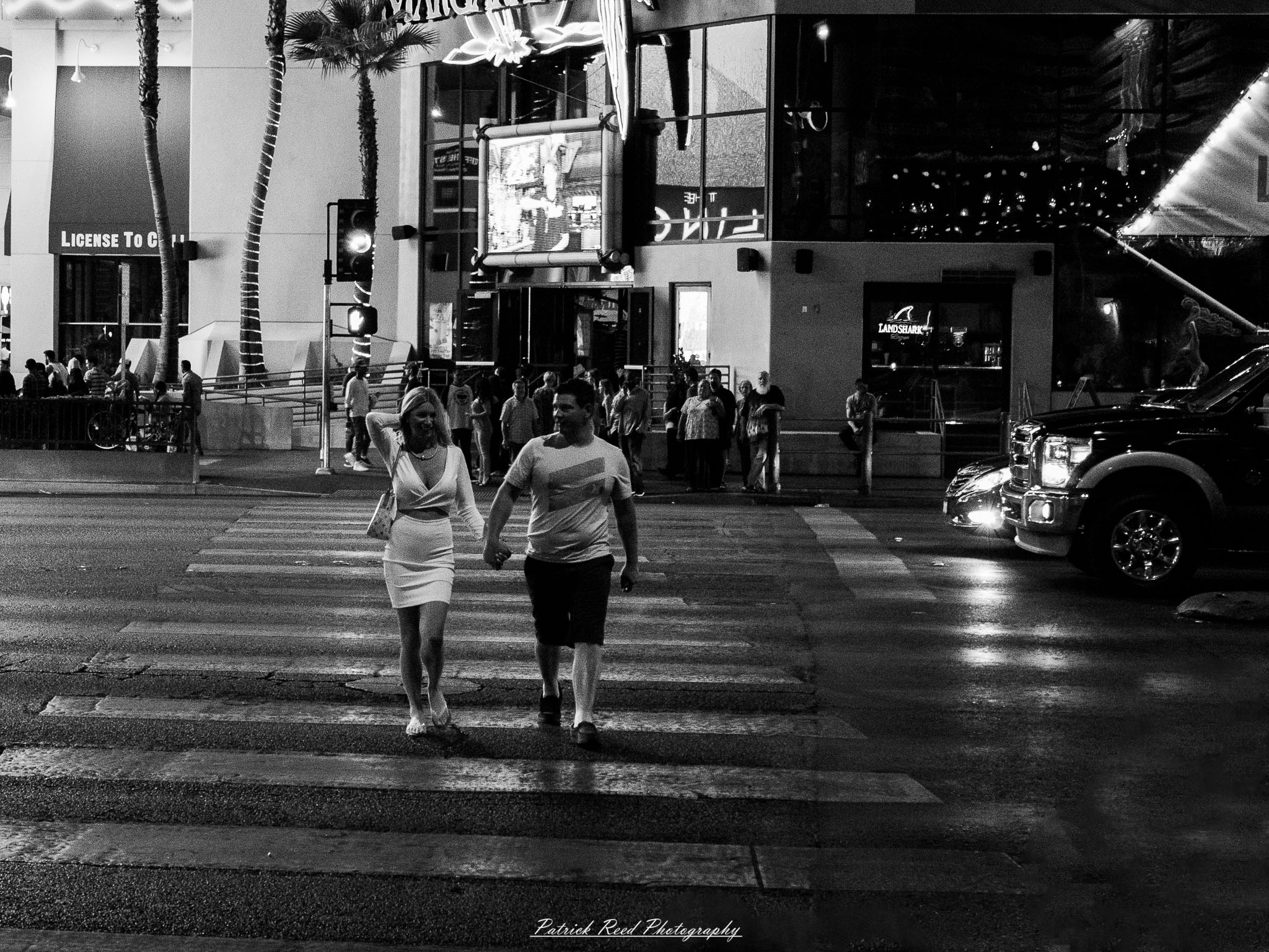 Vegas 13 A series of noir-style street photography scenes set in Las Vegas, Nevada, at night. The rain-slicked streets reflect the vibrant glow of neon signs from casinos, motels, and diners. Silhouettes of people walking under umbrellas or leaning against lampposts add a sense of mystery and intrigue. The scenes capture a mix of classic Vegas landmarks, vintage signage, and gritty back alleys with graffiti and scattered debris. The dramatic lighting emphasizes shadows and contrasts, creating a moody, cinematic ambiance that evokes the essence of noir storytelling in a bustling yet shadowy cityscape.