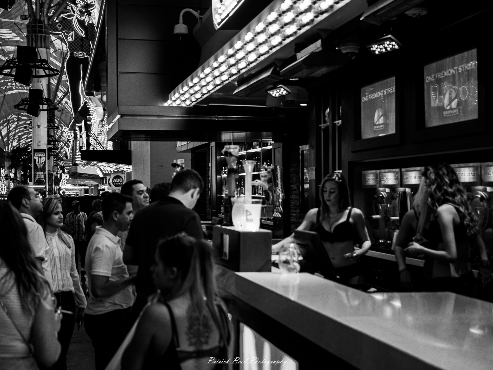 Vegas 17 A series of noir-style street photography scenes set in Las Vegas, Nevada, at night. The rain-slicked streets reflect the vibrant glow of neon signs from casinos, motels, and diners. Silhouettes of people walking under umbrellas or leaning against lampposts add a sense of mystery and intrigue. The scenes capture a mix of classic Vegas landmarks, vintage signage, and gritty back alleys with graffiti and scattered debris. The dramatic lighting emphasizes shadows and contrasts, creating a moody, cinematic ambiance that evokes the essence of noir storytelling in a bustling yet shadowy cityscape.