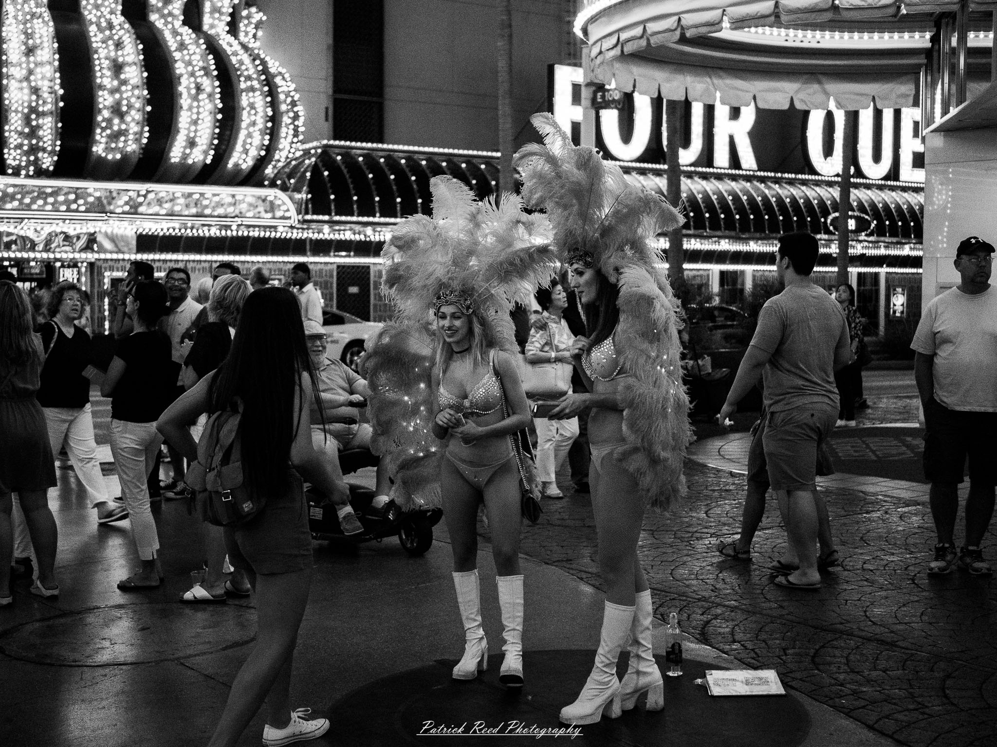 Vegas 23 A series of noir-style street photography scenes set in Las Vegas, Nevada, at night. The rain-slicked streets reflect the vibrant glow of neon signs from casinos, motels, and diners. Silhouettes of people walking under umbrellas or leaning against lampposts add a sense of mystery and intrigue. The scenes capture a mix of classic Vegas landmarks, vintage signage, and gritty back alleys with graffiti and scattered debris. The dramatic lighting emphasizes shadows and contrasts, creating a moody, cinematic ambiance that evokes the essence of noir storytelling in a bustling yet shadowy cityscape.