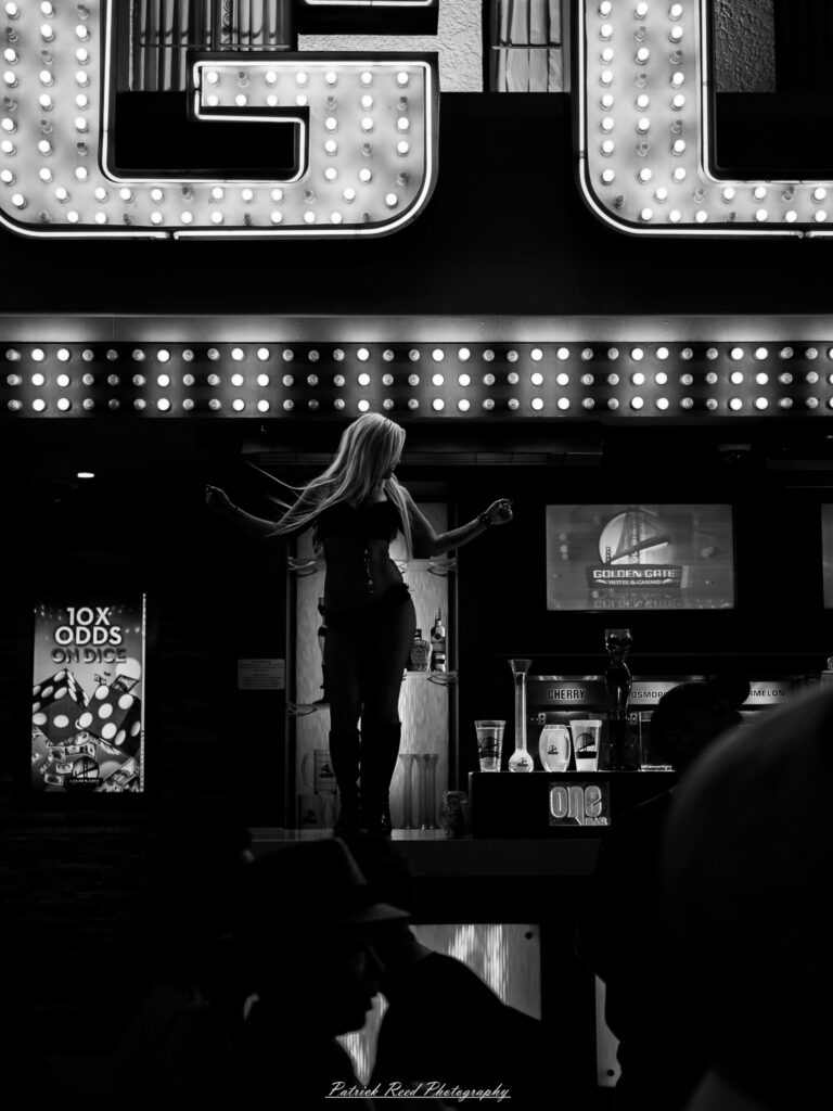 A series of noir-style street photography scenes set in Las Vegas, Nevada, at night. The rain-slicked streets reflect the vibrant glow of neon signs from casinos, motels, and diners. Silhouettes of people walking under umbrellas or leaning against lampposts add a sense of mystery and intrigue. The scenes capture a mix of classic Vegas landmarks, vintage signage, and gritty back alleys with graffiti and scattered debris. The dramatic lighting emphasizes shadows and contrasts, creating a moody, cinematic ambiance that evokes the essence of noir storytelling in a bustling yet shadowy cityscape.