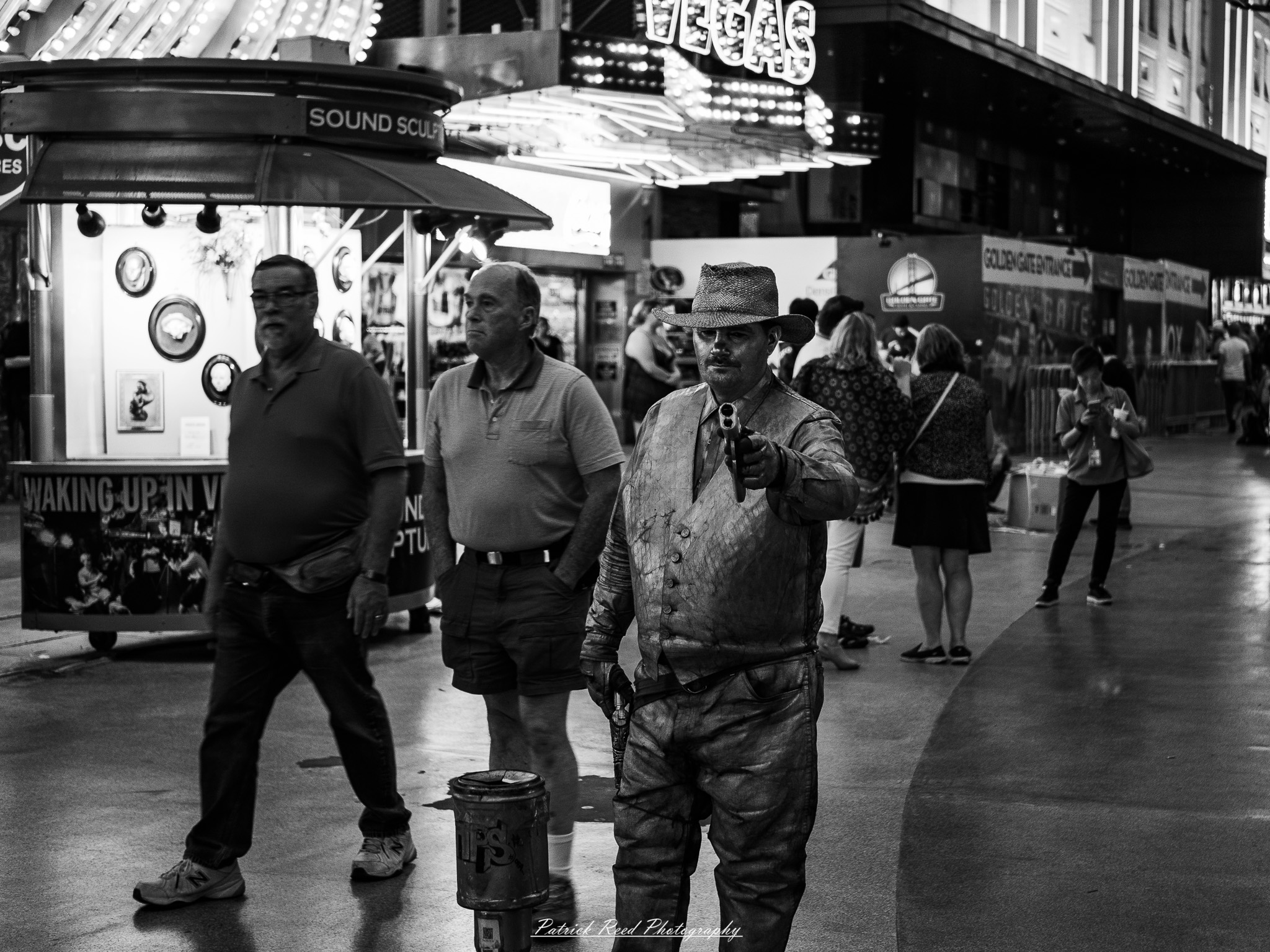 Vegas 4 A series of noir-style street photography scenes set in Las Vegas, Nevada, at night. The rain-slicked streets reflect the vibrant glow of neon signs from casinos, motels, and diners. Silhouettes of people walking under umbrellas or leaning against lampposts add a sense of mystery and intrigue. The scenes capture a mix of classic Vegas landmarks, vintage signage, and gritty back alleys with graffiti and scattered debris. The dramatic lighting emphasizes shadows and contrasts, creating a moody, cinematic ambiance that evokes the essence of noir storytelling in a bustling yet shadowy cityscape.
