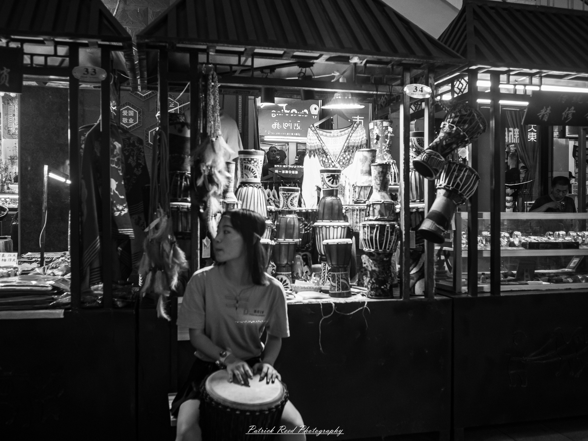 A series of noir-style street photography scenes set in Dunhuang, China, at night. The dimly lit streets and narrow alleyways reflect the soft glow of lanterns and neon signs from small shops and market stalls. Silhouettes of people walk through the misty night, some in traditional robes, adding a sense of mystery. The historic Silk Road atmosphere is highlighted by earthen architecture, intricate wooden doors, and desert dust settling on the pavement. Modern elements like motorbikes and distant headlights contrast with the ancient setting. The deep shadows and warm, flickering lights create a cinematic, moody ambiance, blending noir aesthetics with Dunhuang’s rich cultural history.