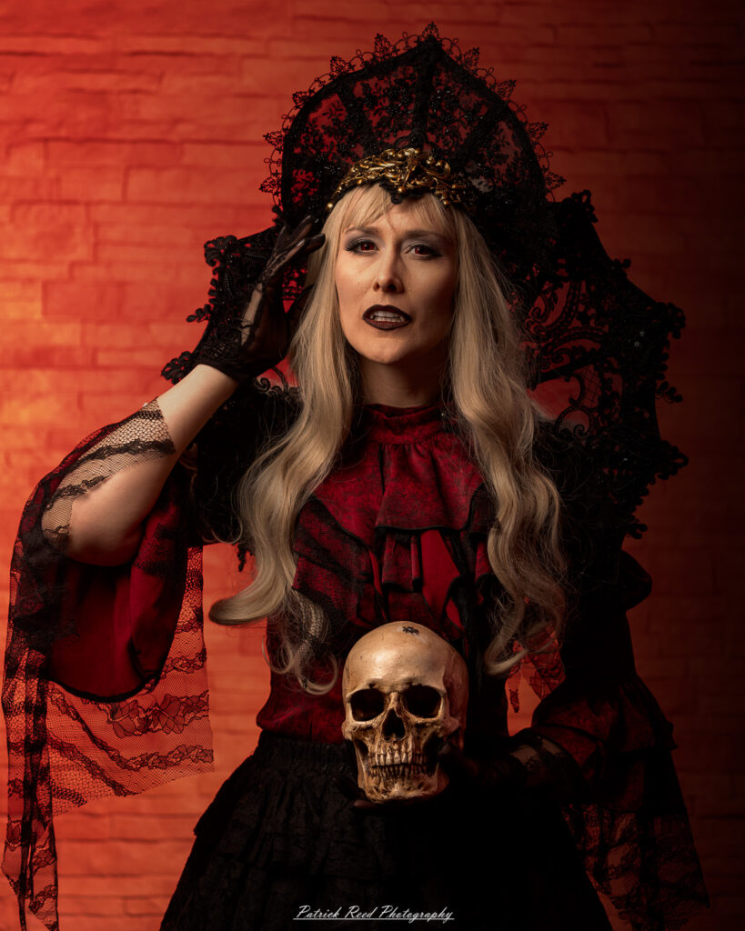 Portrait of a woman in vampire cosplay named Lady Thorn, photographed on June 28, 2025. She is posed against a vivid red background, styled with gothic elements and dramatic expression.