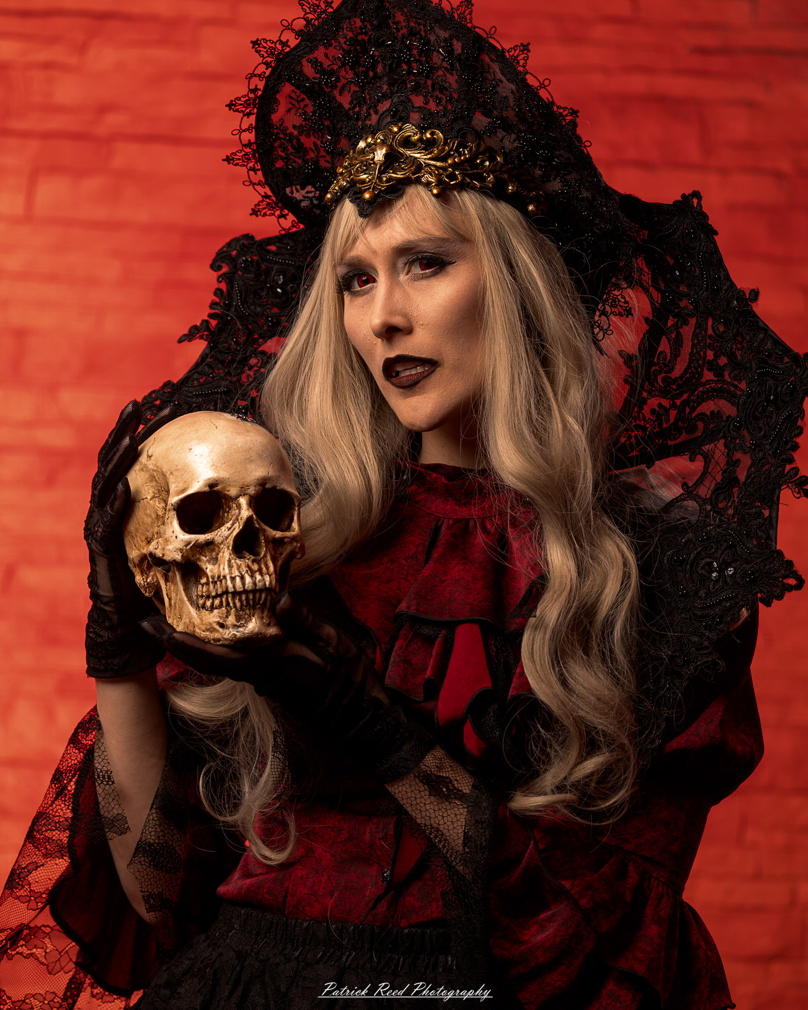 Alt text: Portrait of a woman in vampire cosplay named Lady Thorn, photographed on June 28, 2025. She is posed against a vivid red background, styled with gothic elements and dramatic expression.