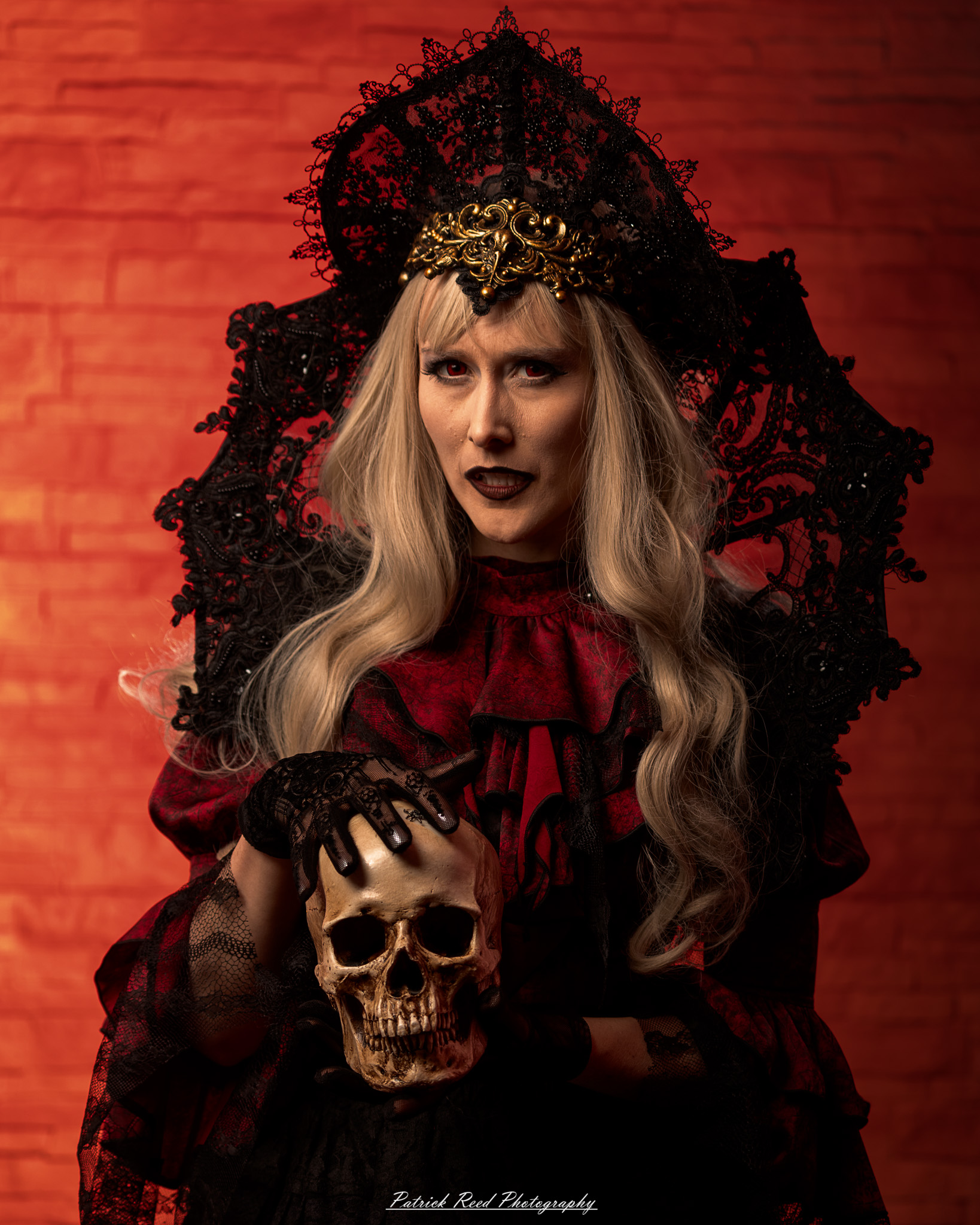 Portrait of a woman in vampire cosplay named Lady Thorn, photographed on June 28, 2025. She is posed against a vivid red background, styled with gothic elements and dramatic expression.