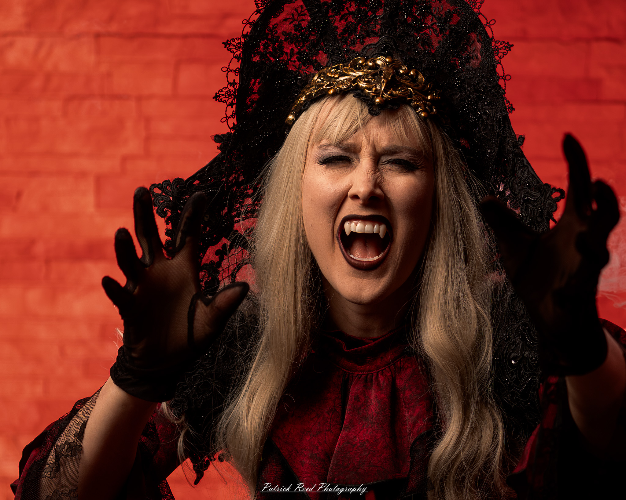 Portrait of a woman in vampire cosplay named Lady Thorn, photographed on June 28, 2025. She is posed against a vivid red background, styled with gothic elements and dramatic expression.