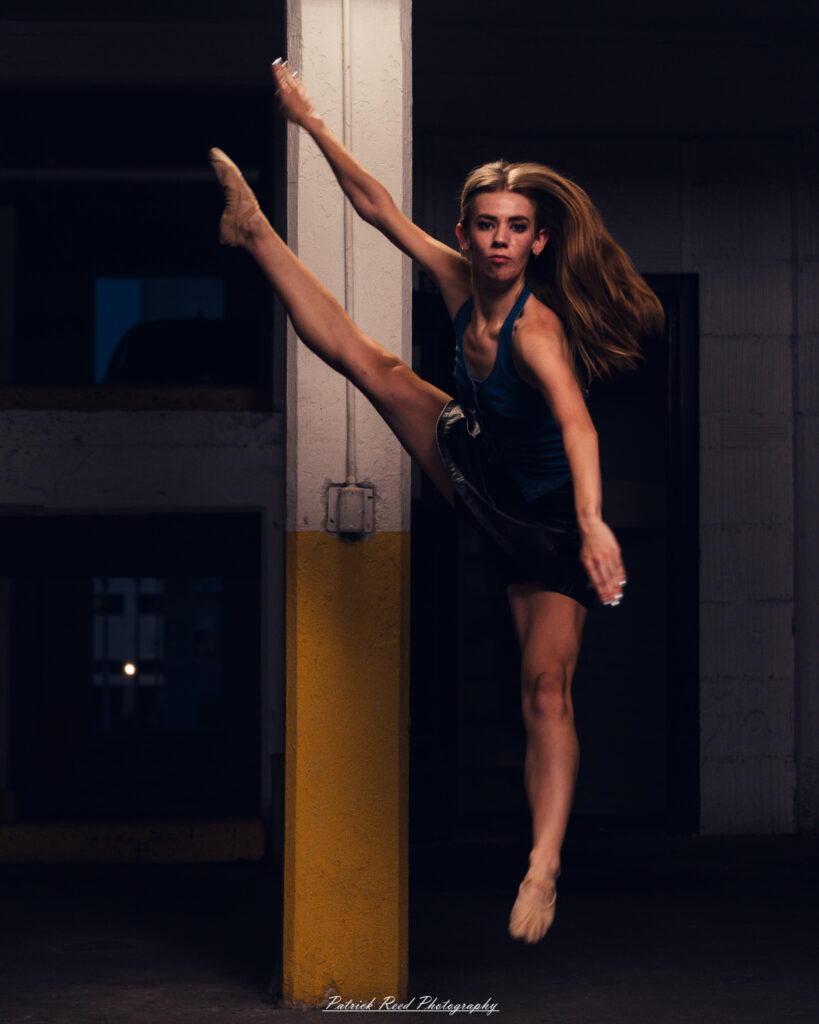 Portrait of a ballet dancer photographed on July 30, 2025, in a parking garage in Pontiac, Michigan. The dancer strikes a poised, elegant pose against the gritty urban backdrop.