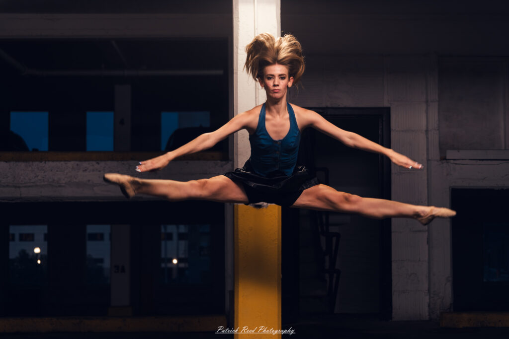 Portrait of a ballet dancer photographed on July 30, 2025, in a parking garage in Pontiac, Michigan. The dancer strikes a poised, elegant pose against the gritty urban backdrop.