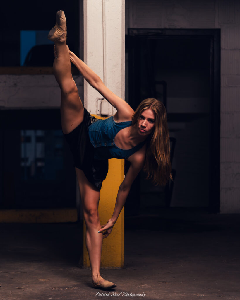 Portrait of a ballet dancer photographed on July 30, 2025, in a parking garage in Pontiac, Michigan. The dancer strikes a poised, elegant pose against the gritty urban backdrop.