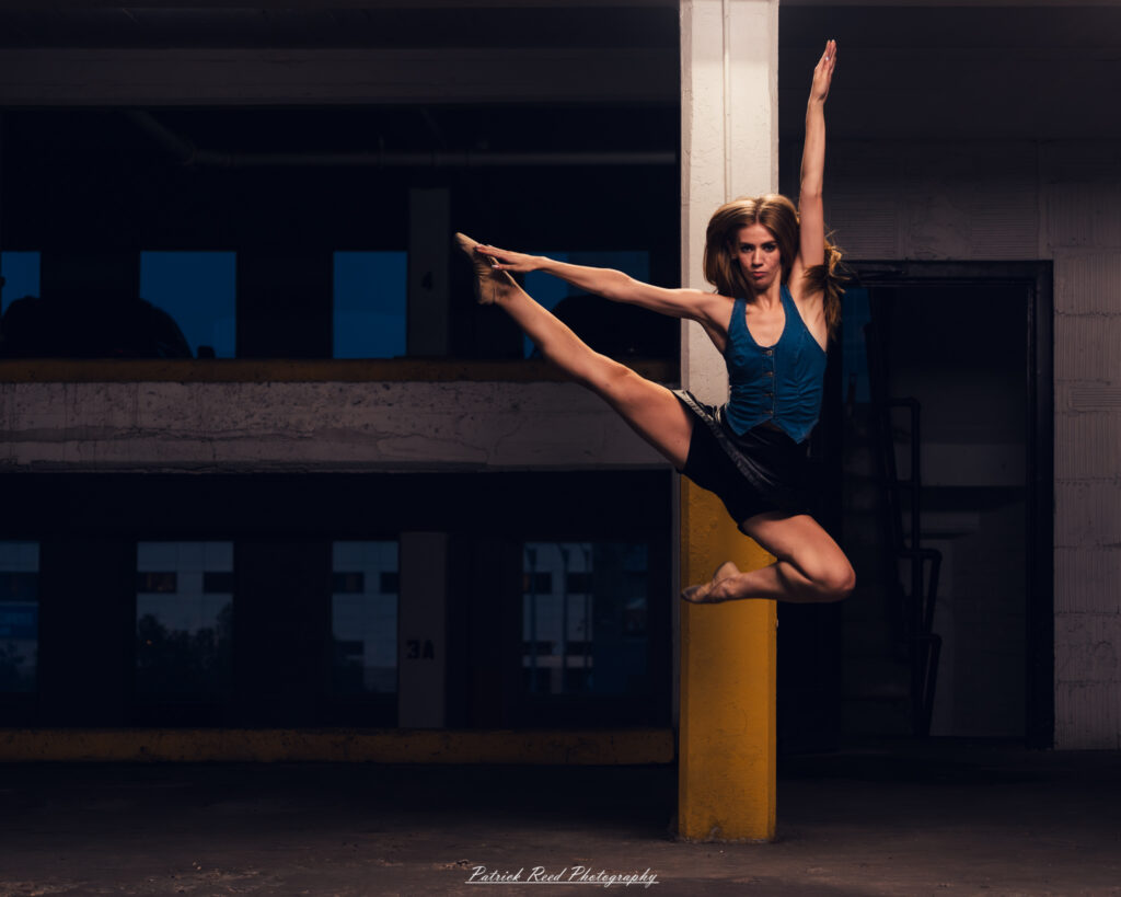 Portrait of a ballet dancer photographed on July 30, 2025, in a parking garage in Pontiac, Michigan. The dancer strikes a poised, elegant pose against the gritty urban backdrop.