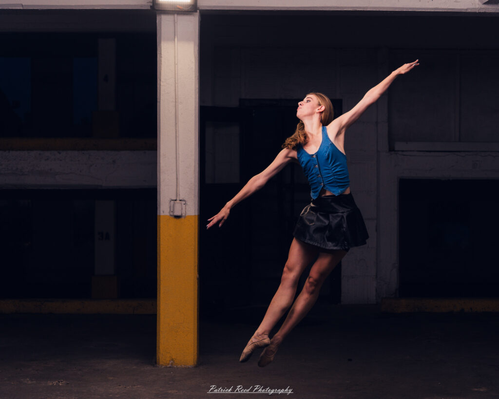 Portrait of a ballet dancer photographed on July 30, 2025, in a parking garage in Pontiac, Michigan. The dancer strikes a poised, elegant pose against the gritty urban backdrop.