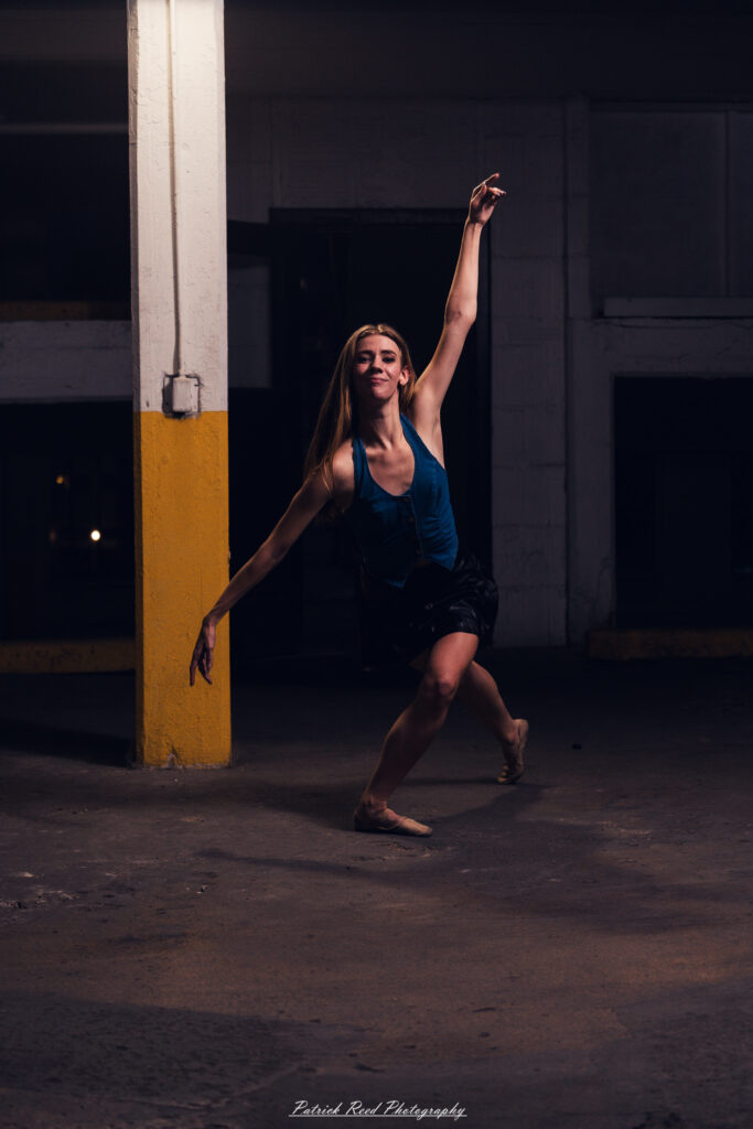 Portrait of a ballet dancer photographed on July 30, 2025, in a parking garage in Pontiac, Michigan. The dancer strikes a poised, elegant pose against the gritty urban backdrop.