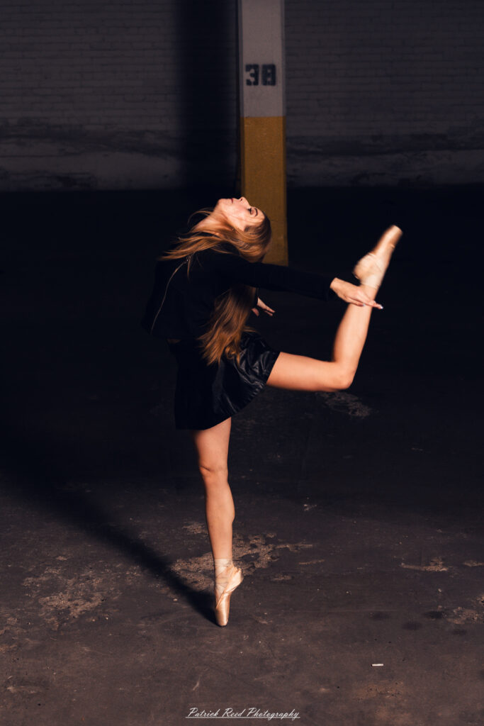 Portrait of a ballet dancer photographed on July 30, 2025, in a parking garage in Pontiac, Michigan. The dancer strikes a poised, elegant pose against the gritty urban backdrop.