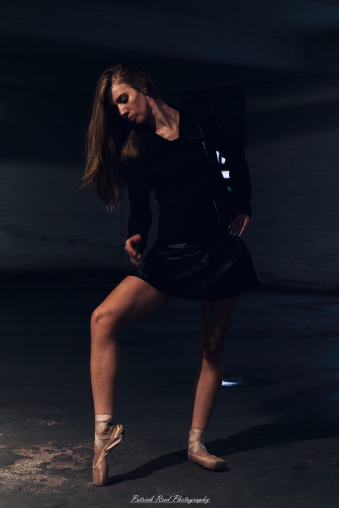 Portrait of a ballet dancer photographed on July 30, 2025, in a parking garage in Pontiac, Michigan. The dancer strikes a poised, elegant pose against the gritty urban backdrop.