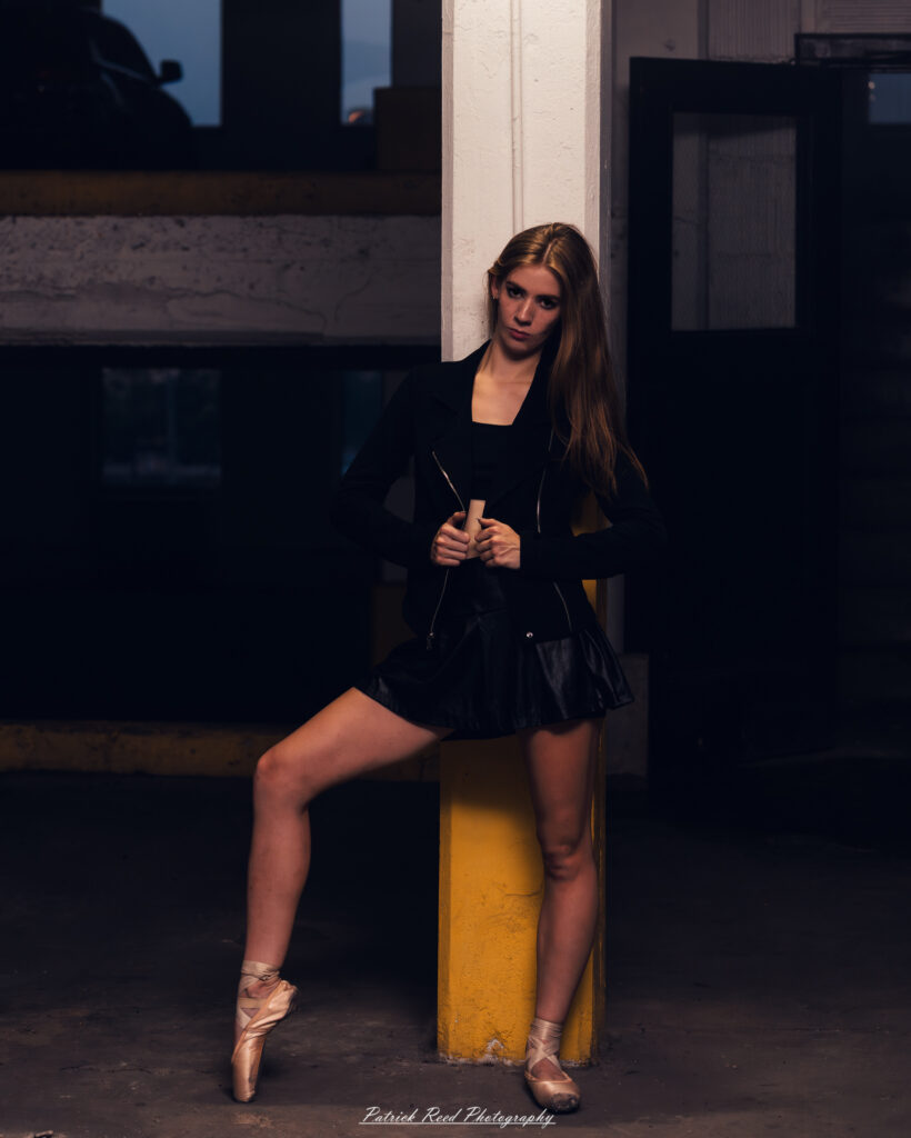Portrait of a ballet dancer photographed on July 30, 2025, in a parking garage in Pontiac, Michigan. The dancer strikes a poised, elegant pose against the gritty urban backdrop.