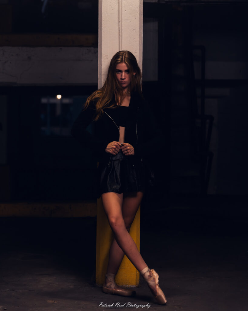 Portrait of a ballet dancer photographed on July 30, 2025, in a parking garage in Pontiac, Michigan. The dancer strikes a poised, elegant pose against the gritty urban backdrop.