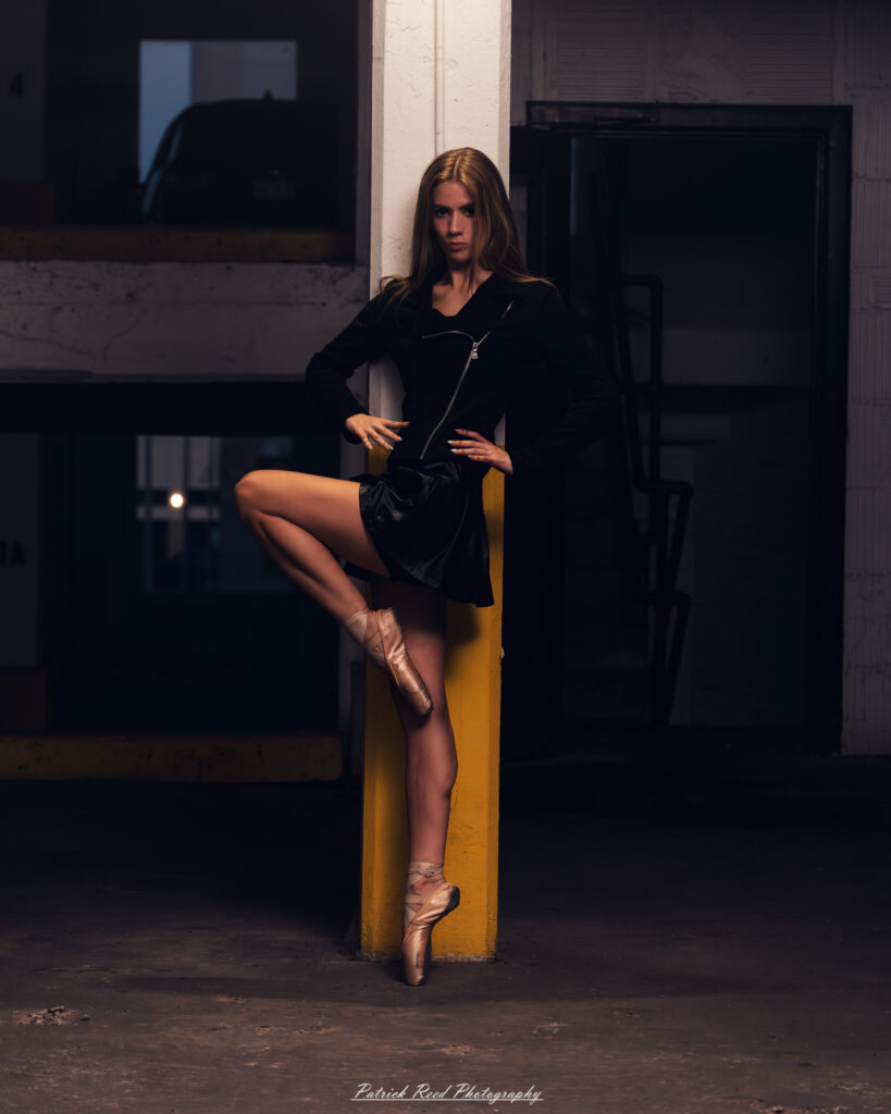 Portrait of a ballet dancer photographed on July 30, 2025, in a parking garage in Pontiac, Michigan. The dancer strikes a poised, elegant pose against the gritty urban backdrop.