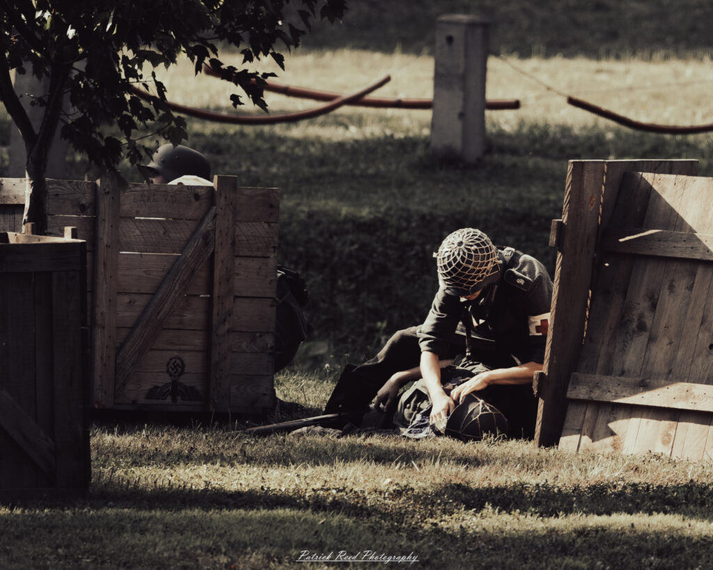 A group of World War II reenactors in period-accurate uniforms—American, German, and French Resistance—on a sandy shore during the D-Day Conneaut 2025 reenactment at Conneaut Township Park, Ohio.